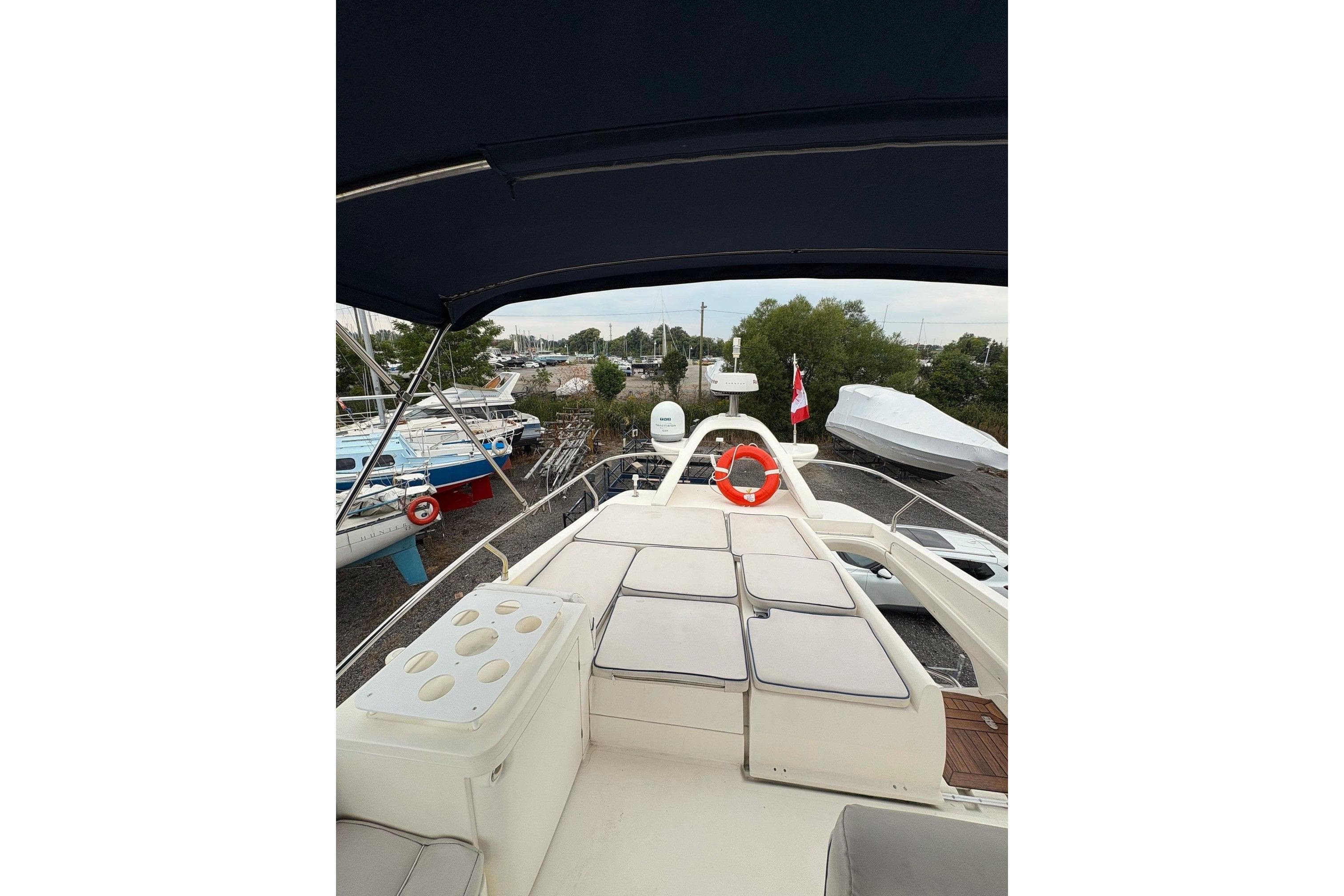2003 Sealine F42/5 yacht deck with seating and canopy, docked in a marina.