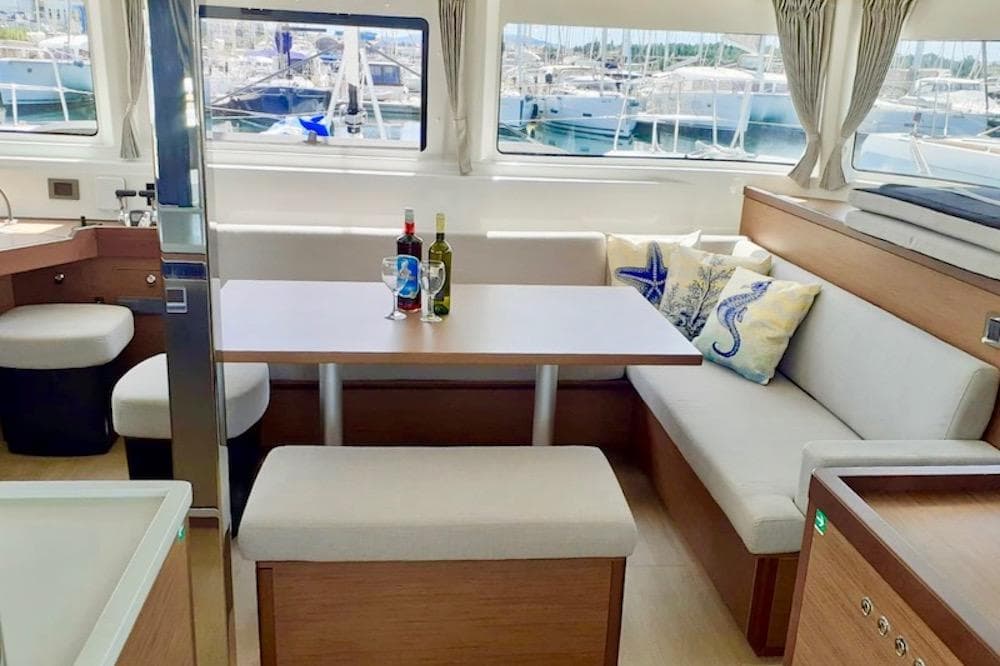 Interior of 2021 Lagoon 46 catamaran with cozy seating and dining area, featuring nautical decor.