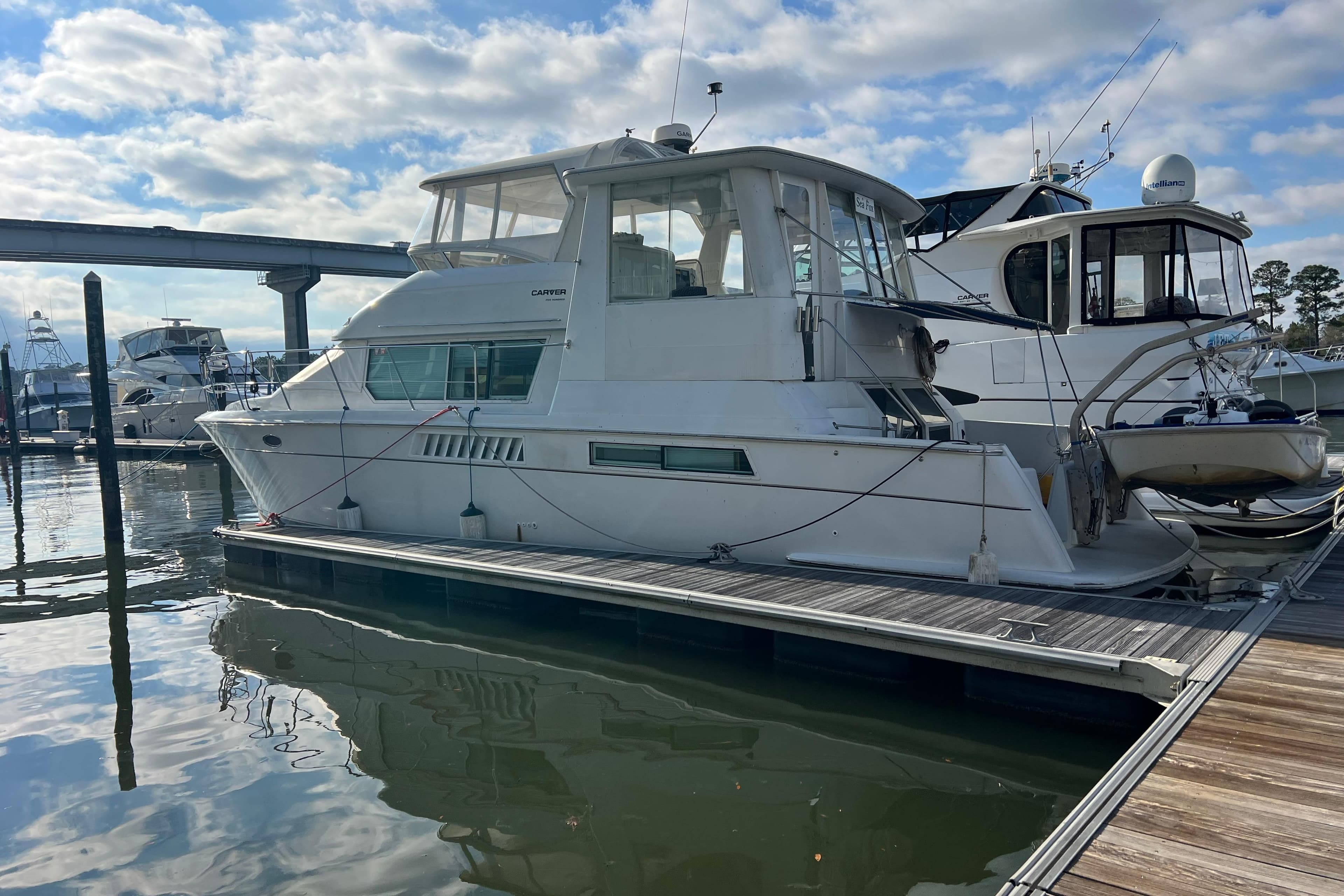 1997 Carver 500 Cockpit Motor Yacht docked at marina under cloudy sky.