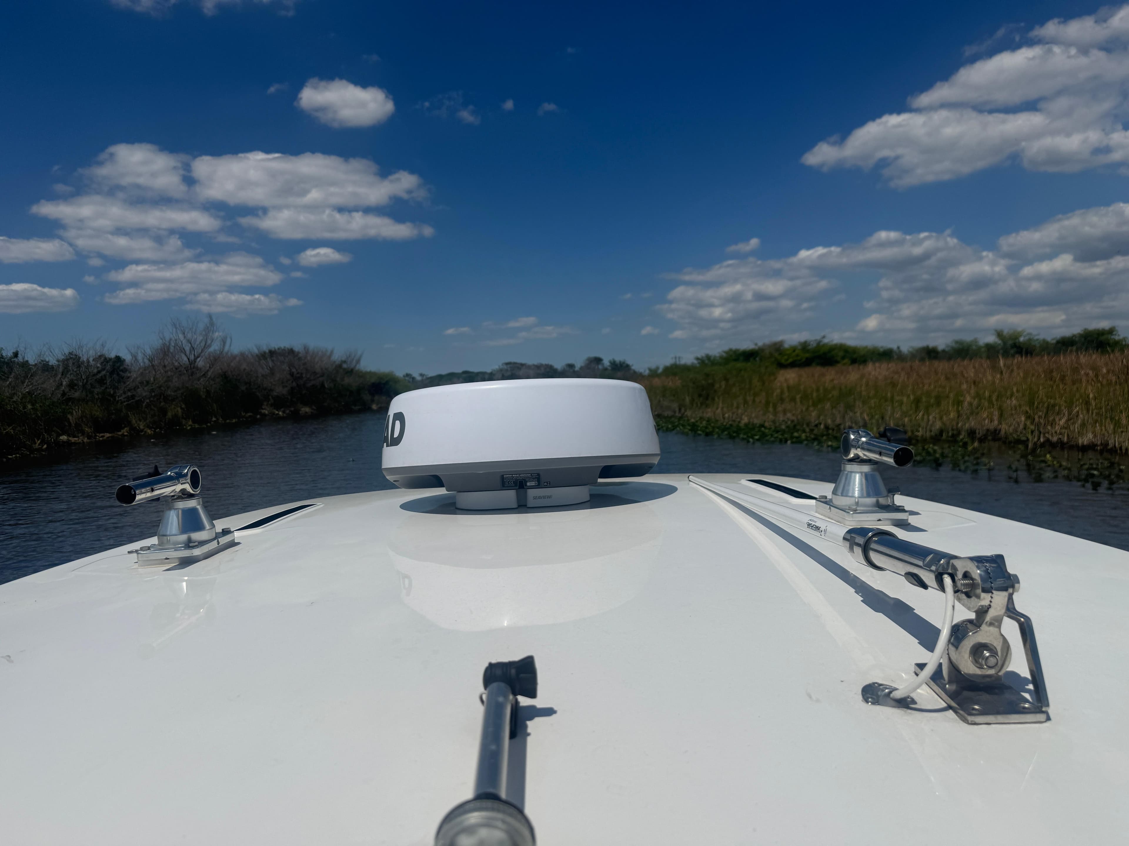 2023 Yamaha Boats 255 FSH Sport E navigating a serene waterway under a blue sky.