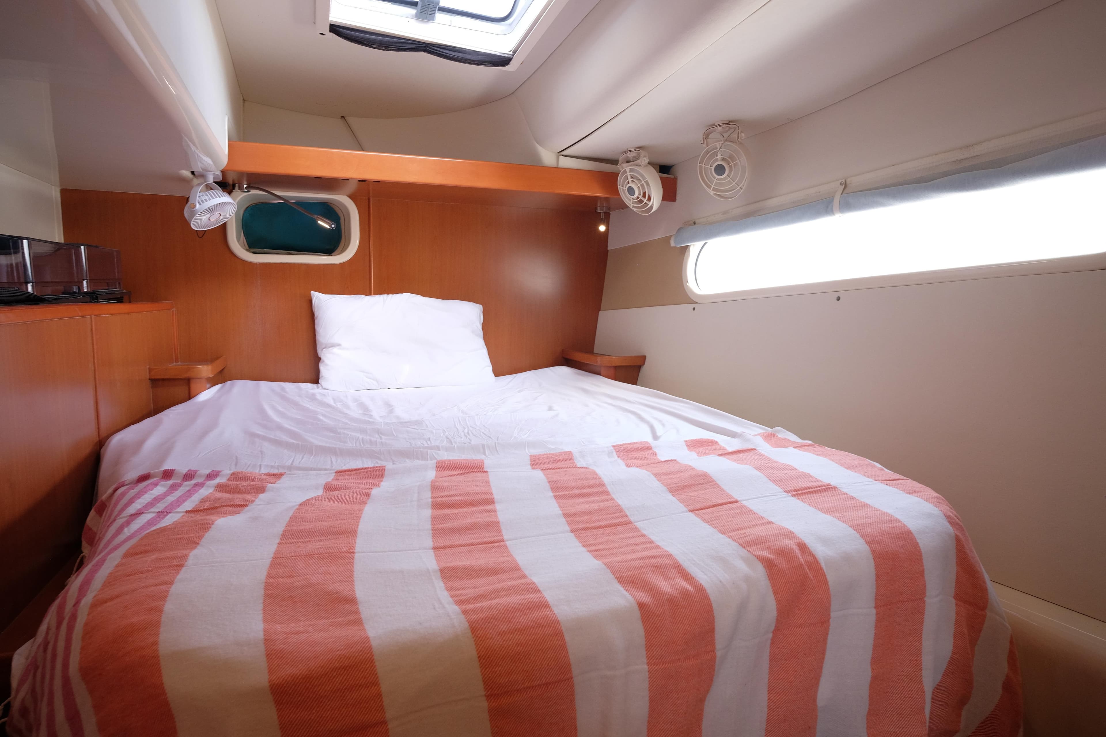 Cozy cabin interior of 2009 Leopard 46 yacht with striped bedding and wooden accents.