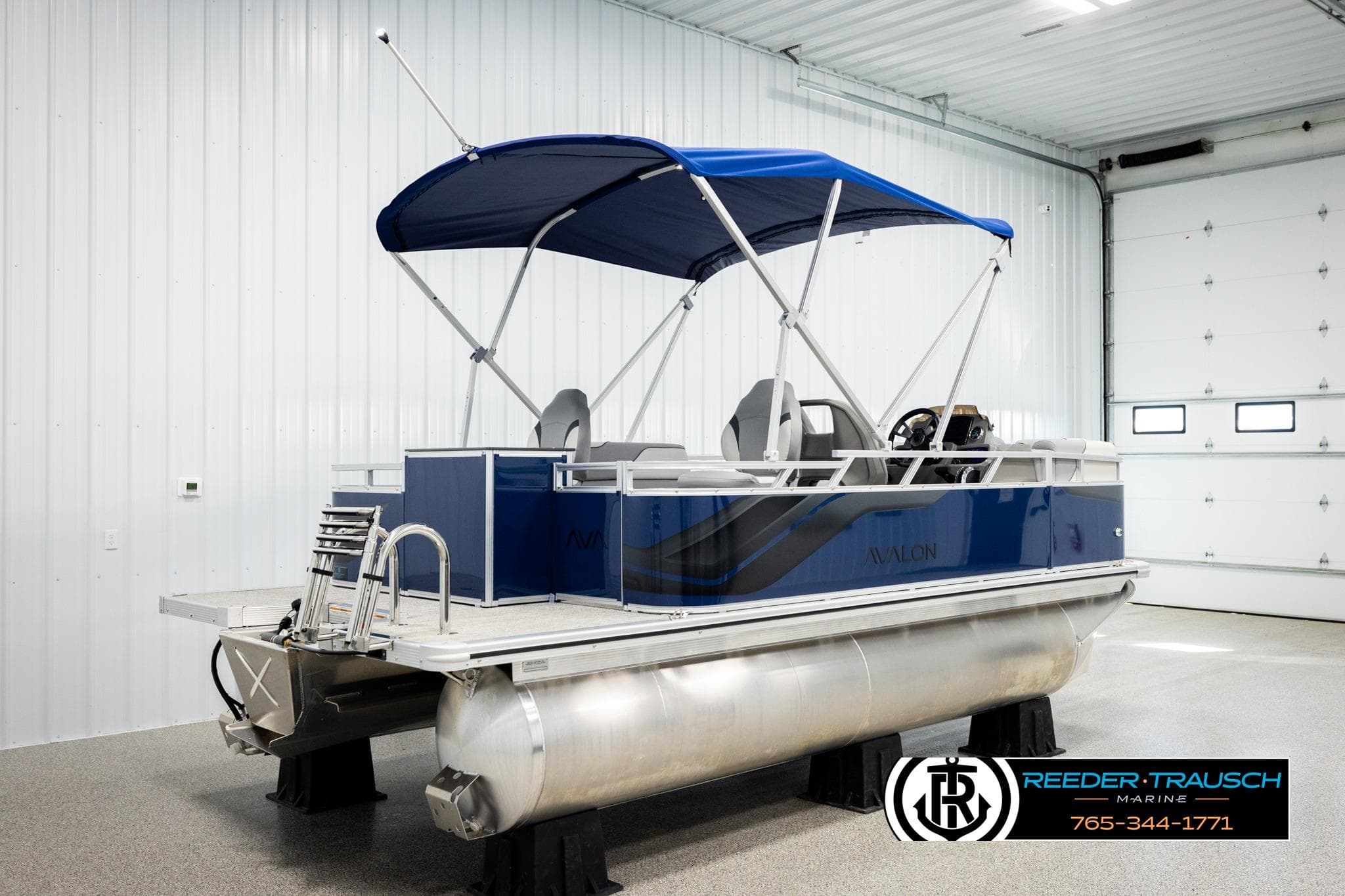 2026 Avalon VEN RF pontoon boat with blue canopy in a showroom.