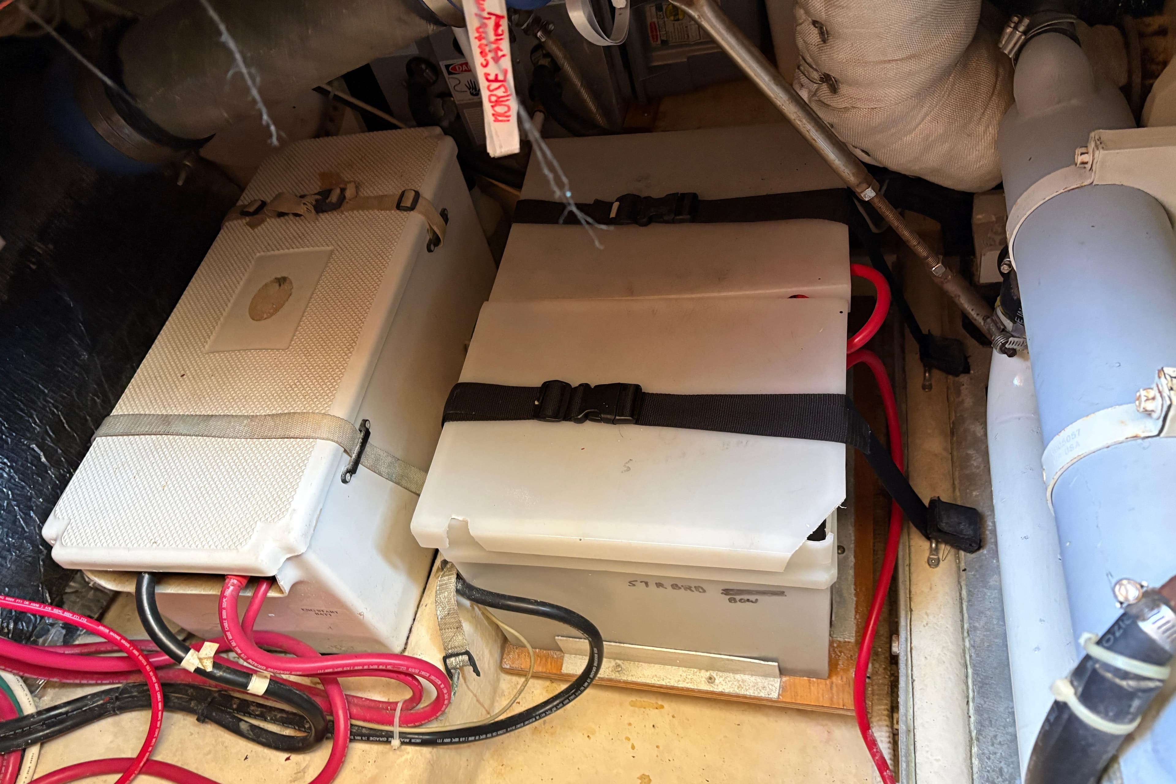 Battery compartment of a 2004 Nordic Tug 32 with secured cables and components.