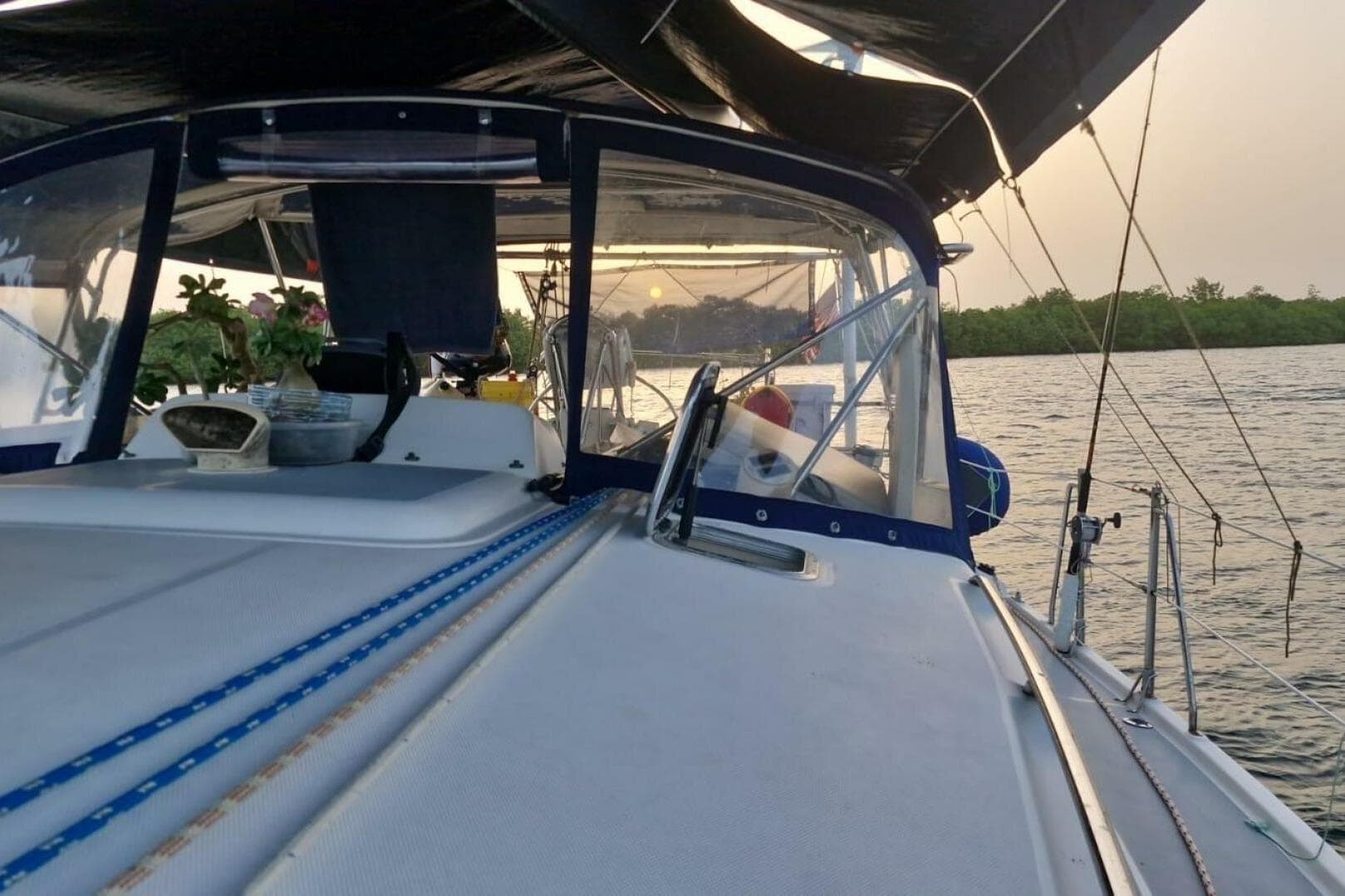Sailing on a 2004 Hunter 44 yacht at sunset, with lush greenery in the background.