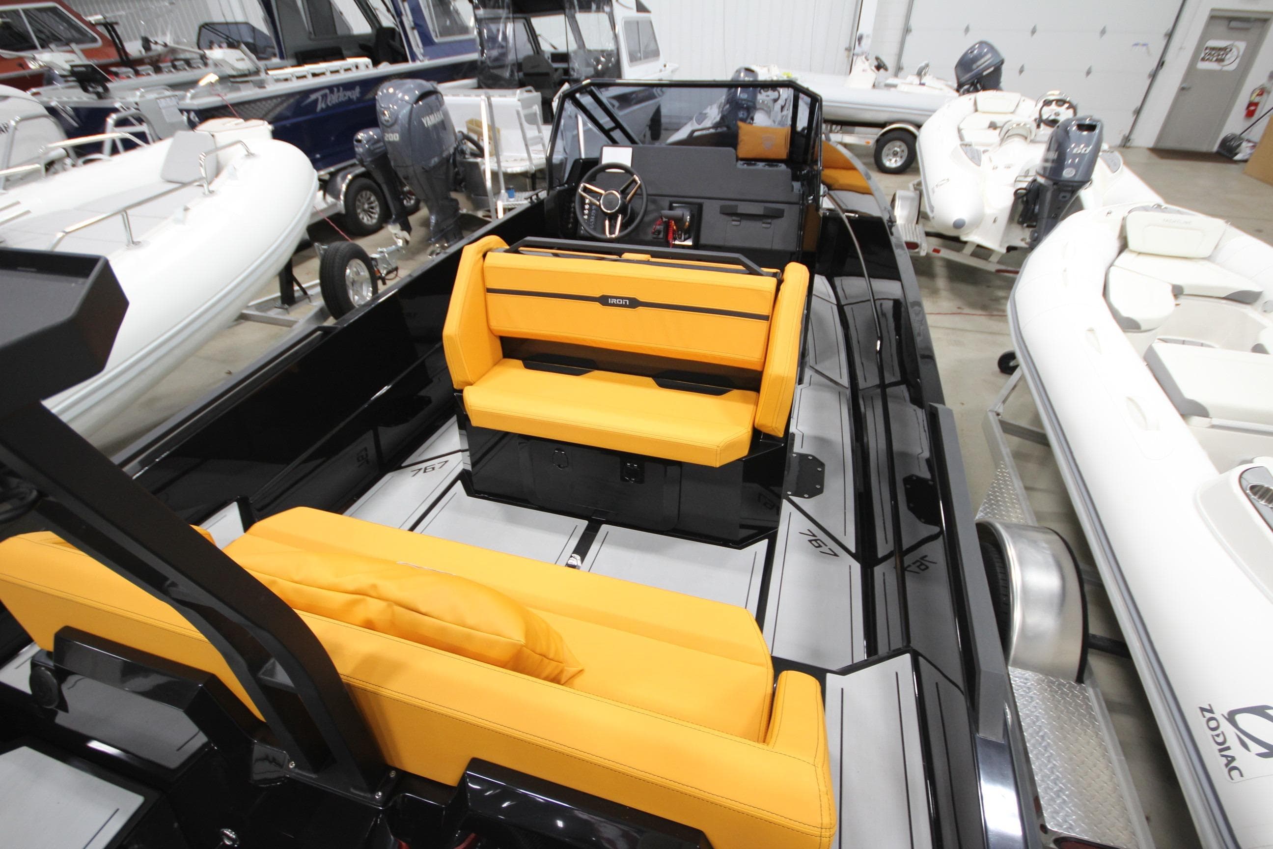2026 Iron 767 T-top boat with vibrant orange seating in a showroom.