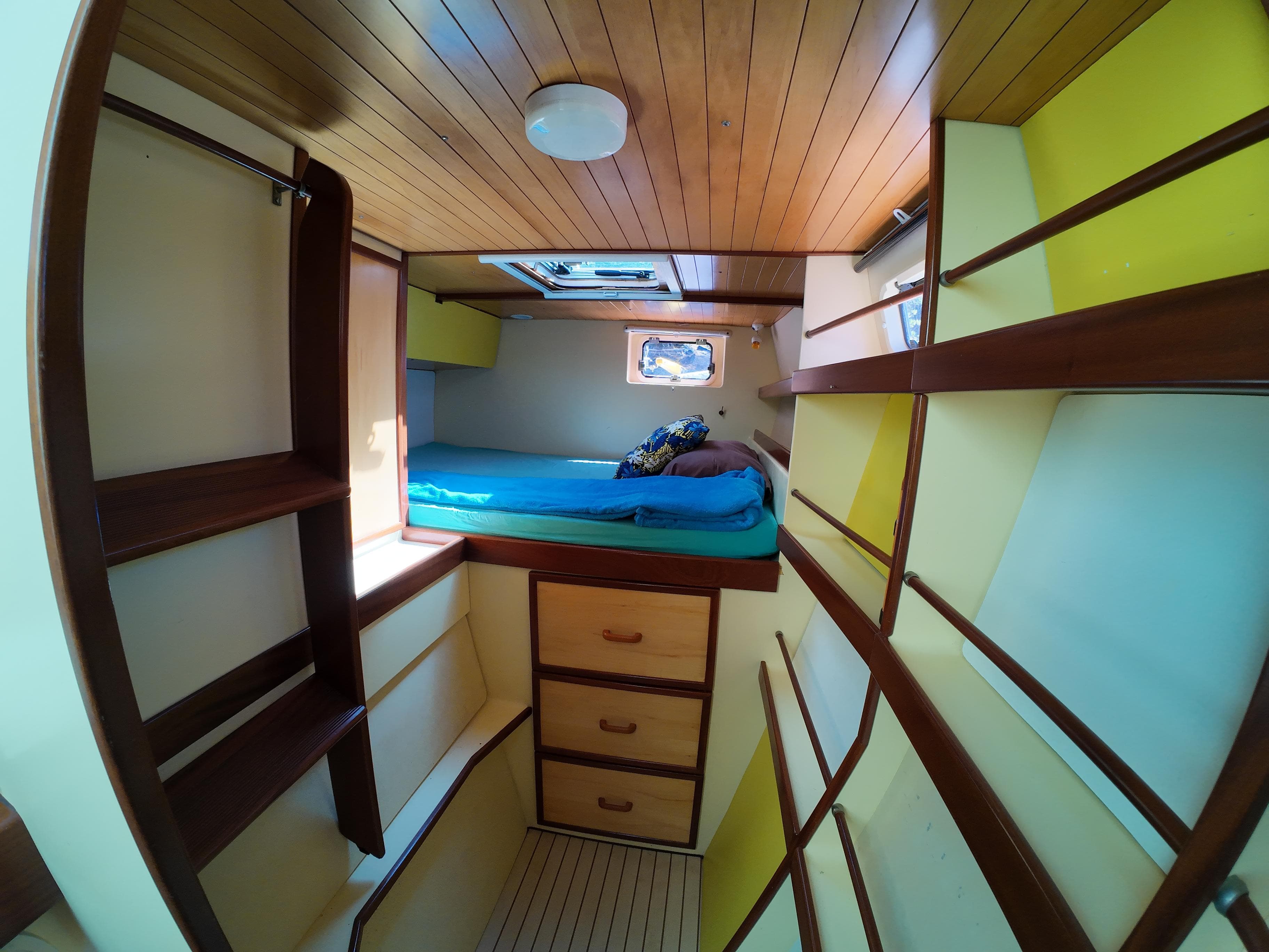 Cozy cabin interior of 2006 Custom Piana 40 yacht with wooden shelves and bed.