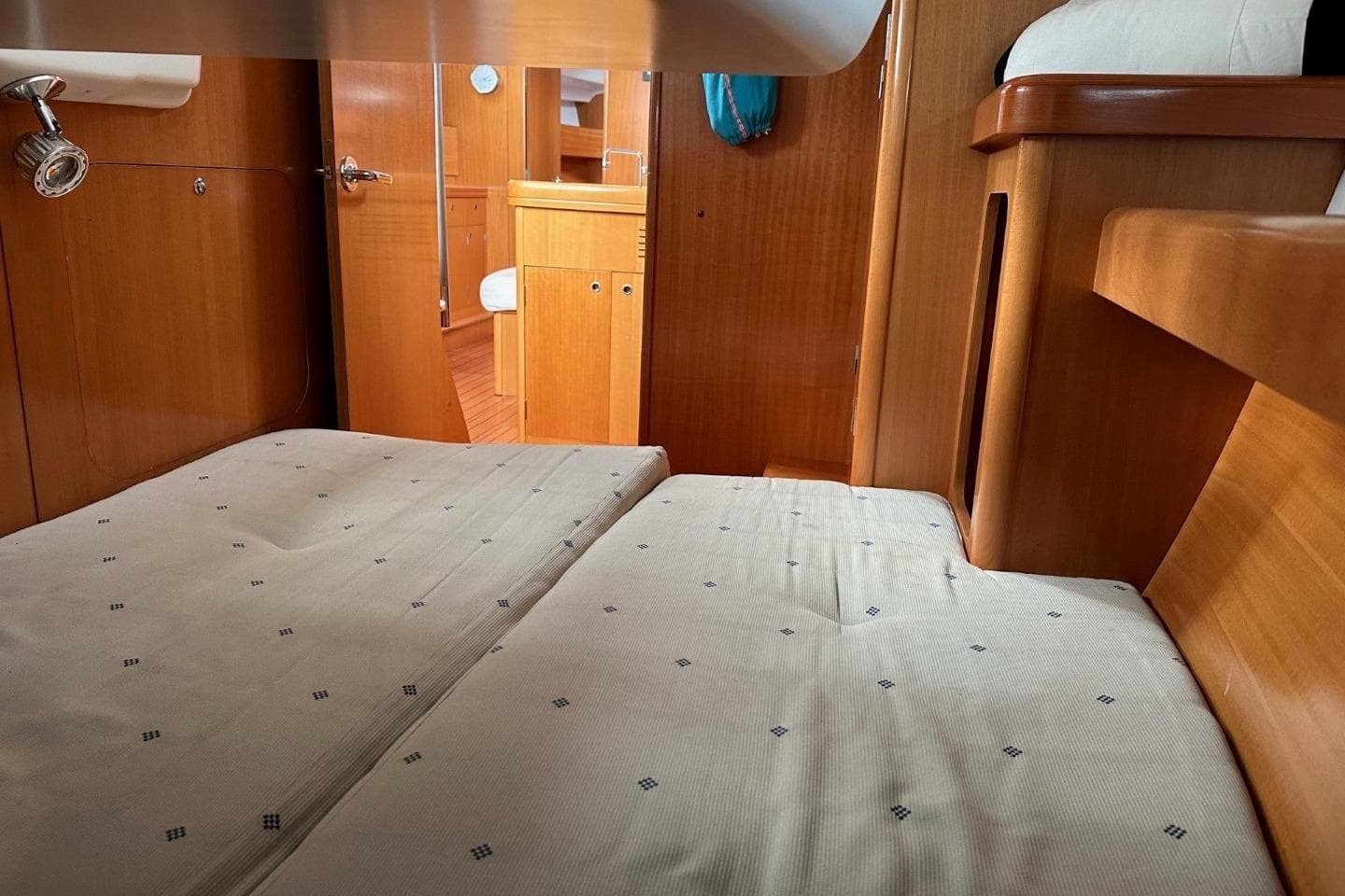 Interior cabin of a 2007 Beneteau First 44.7 yacht with wooden finishes and cozy bedding.
