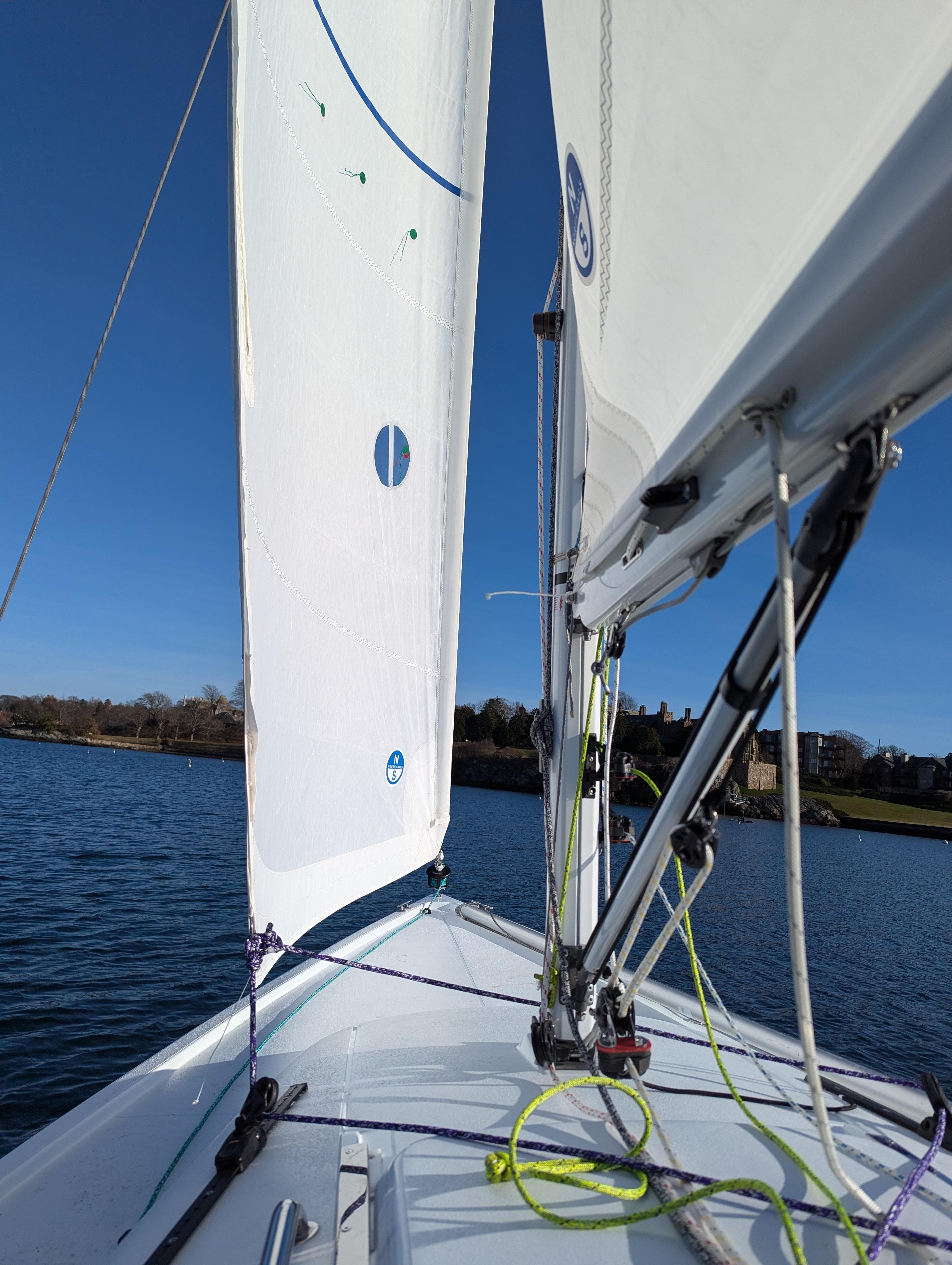 2025 J Boats J 7 sailboat on calm water, clear blue sky.