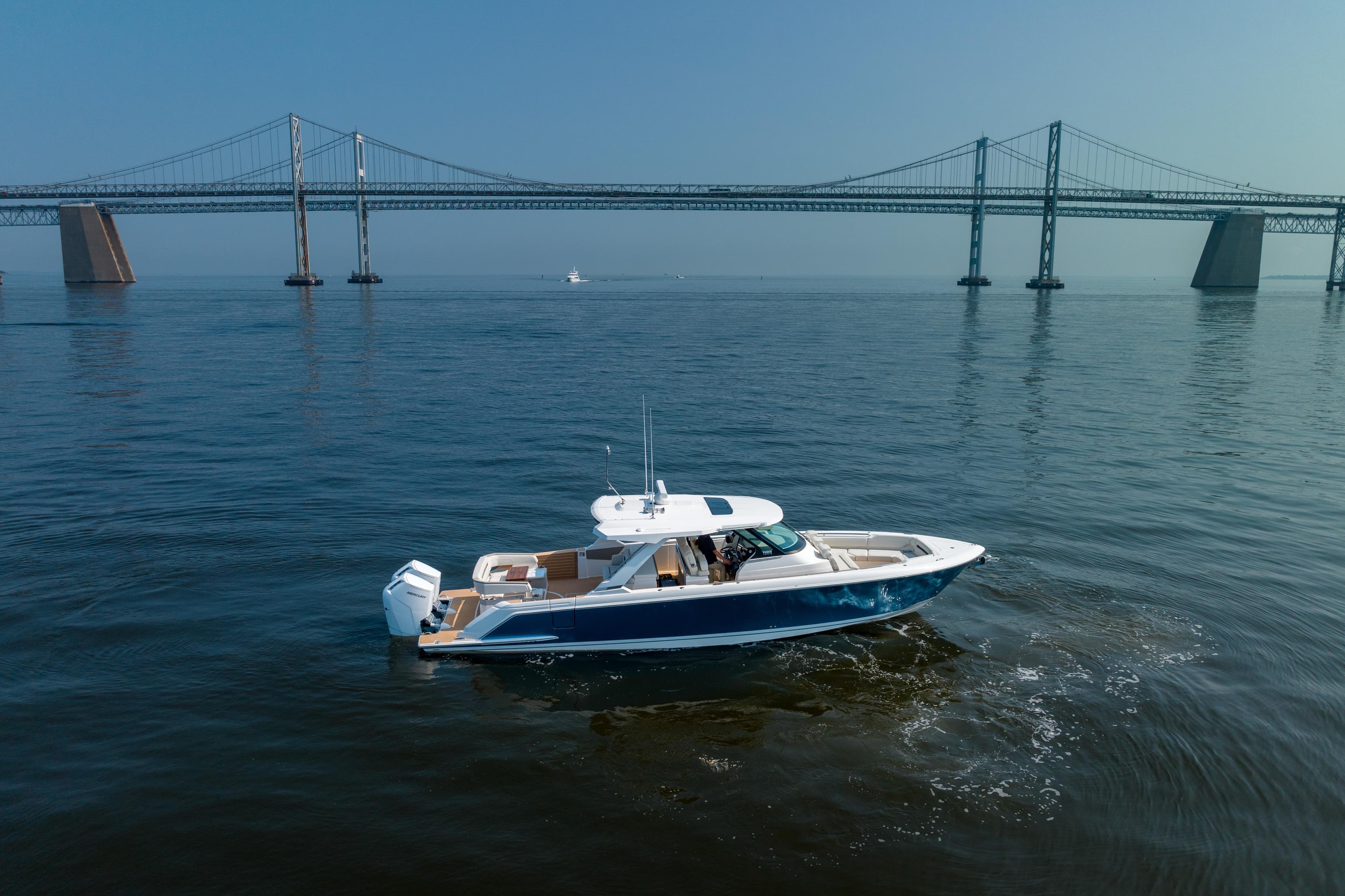 2024 Tiara Yachts 43 LS cruising near a large bridge on calm waters.