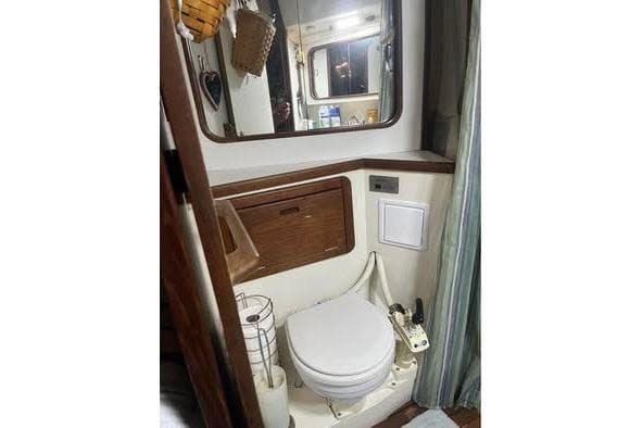 1989 Catalina 42 yacht bathroom with toilet, mirror, and wooden cabinetry.