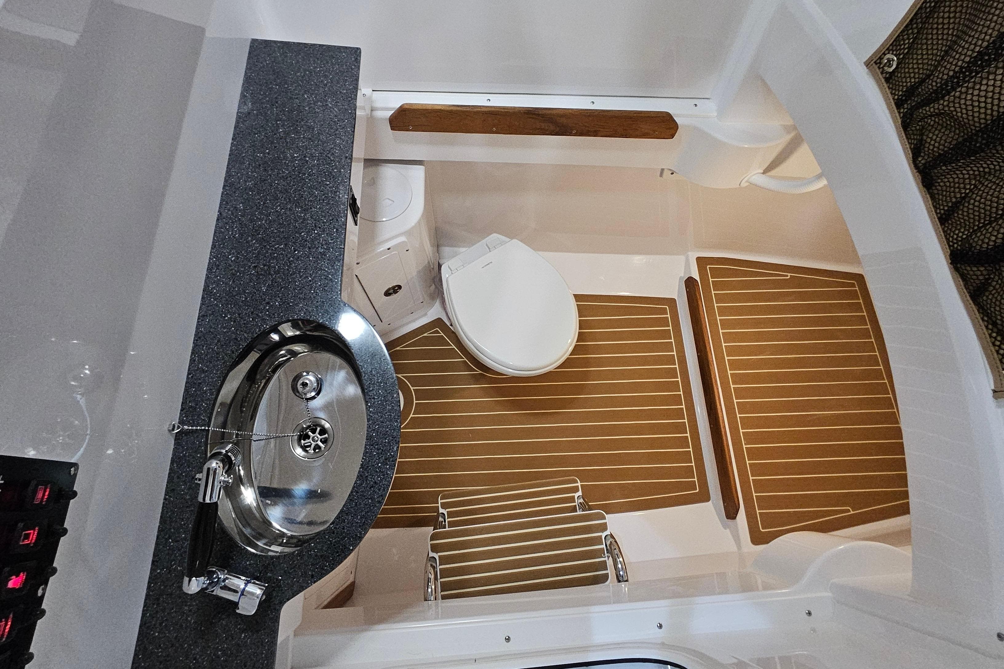 2026 Southport 30 FE boat interior with sink, toilet, and wooden flooring.