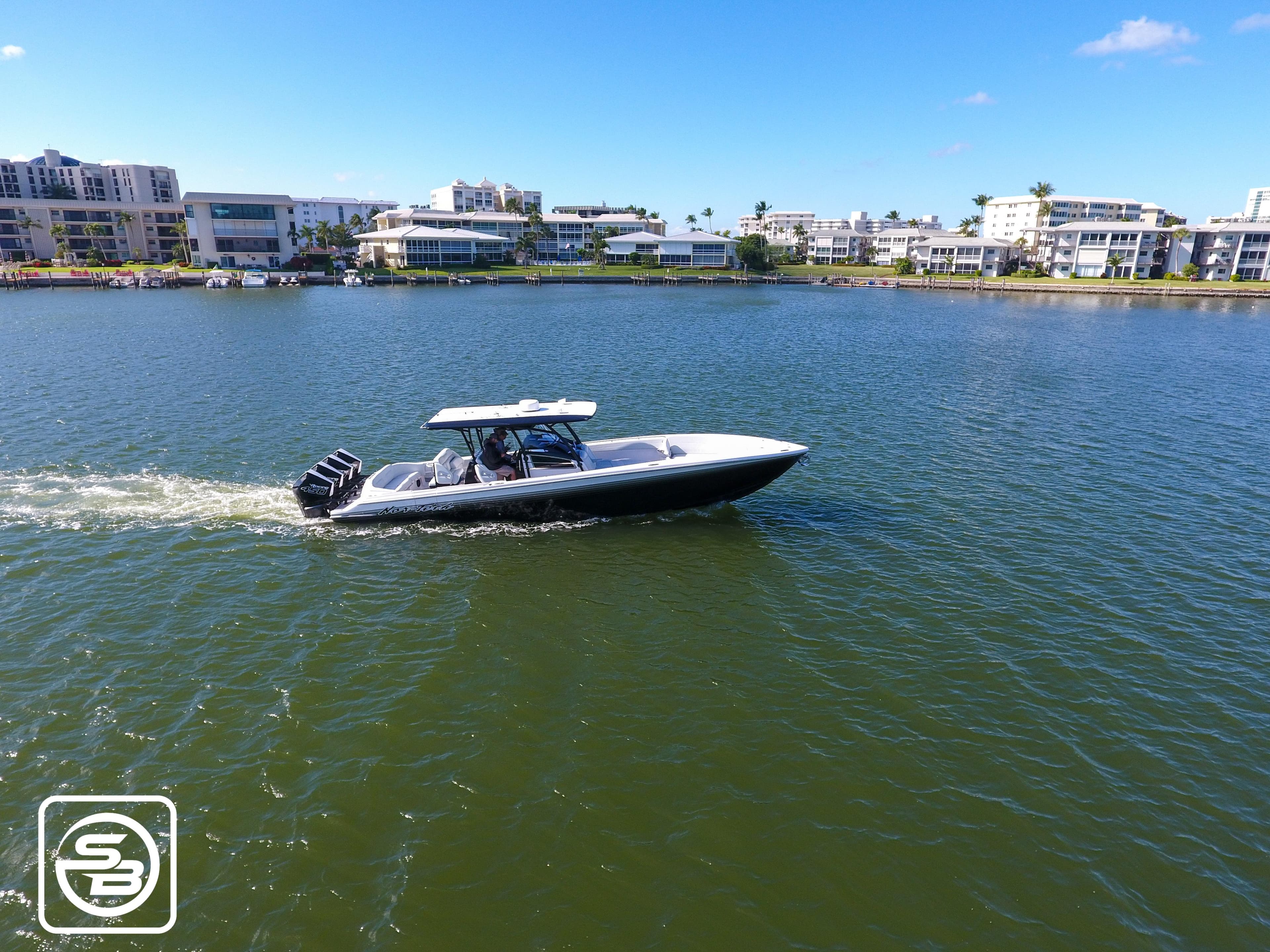 2021 Nor-Tech 390 Sport boat cruising on a sunny day near waterfront buildings.