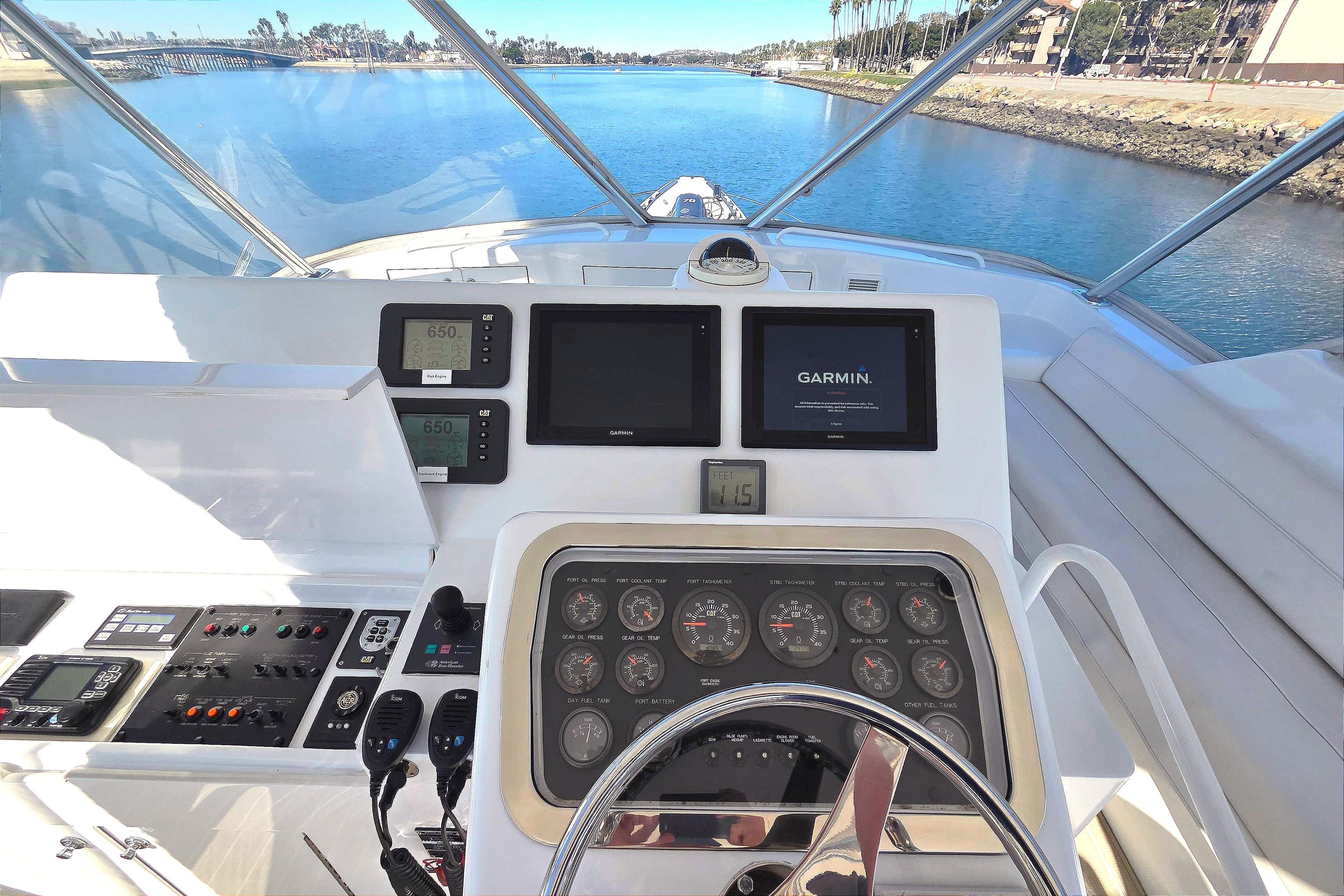 Helm of 2006 Hatteras 50 Convertible yacht with navigation instruments and scenic waterway view.