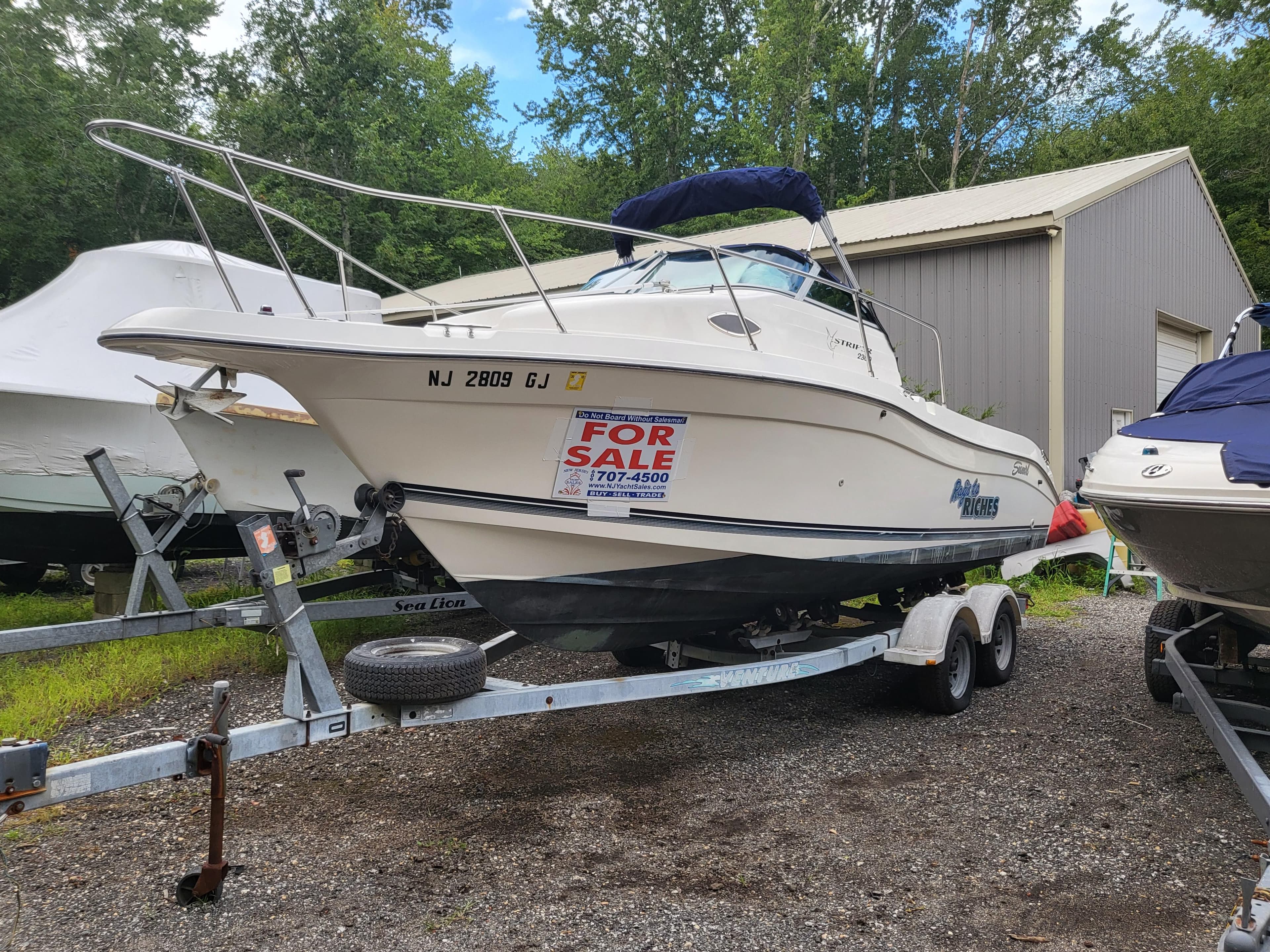 1998 Seaswirl 2300 Walkaround boat for sale on trailer, parked outdoors.