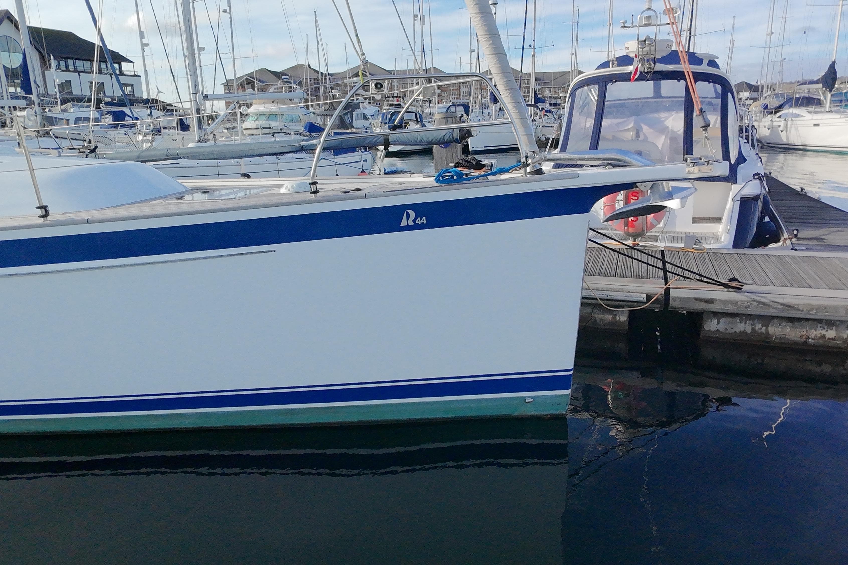 2019 Hallberg-Rassy 44 yacht docked in a marina, showcasing sleek design and blue accents.