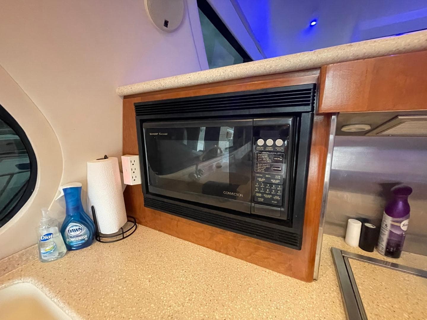 Microwave in 1998 Carver 530 Voyager Pilothouse kitchen with cleaning supplies nearby.