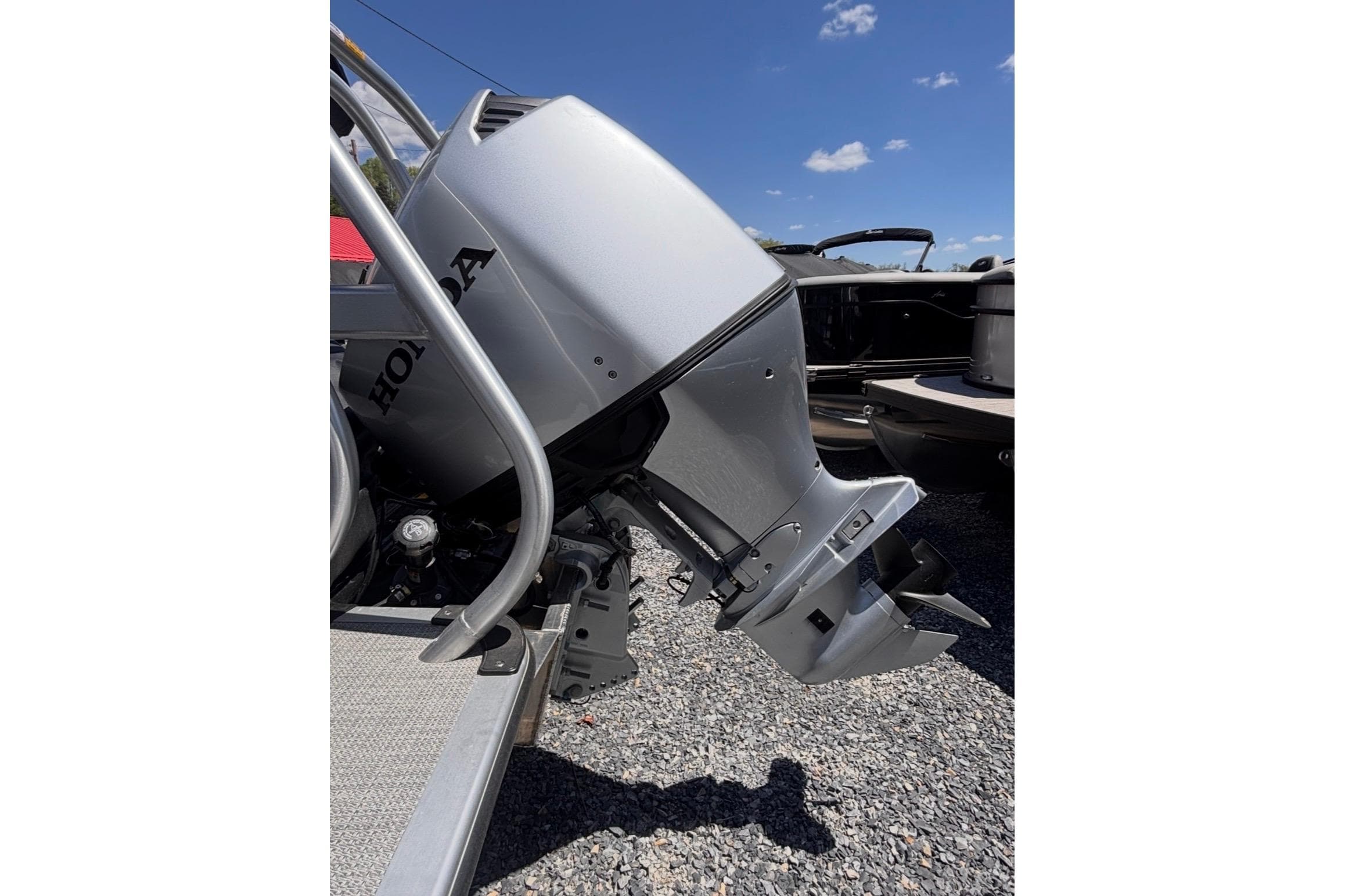 2026 Bentley Pontoons Legacy 220 Cruise XL with Honda outboard motor, parked on gravel.