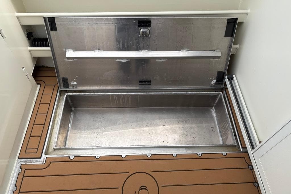 Open storage compartment on Ortun EC276 boat, 2025 model, with metal interior and wooden deck.