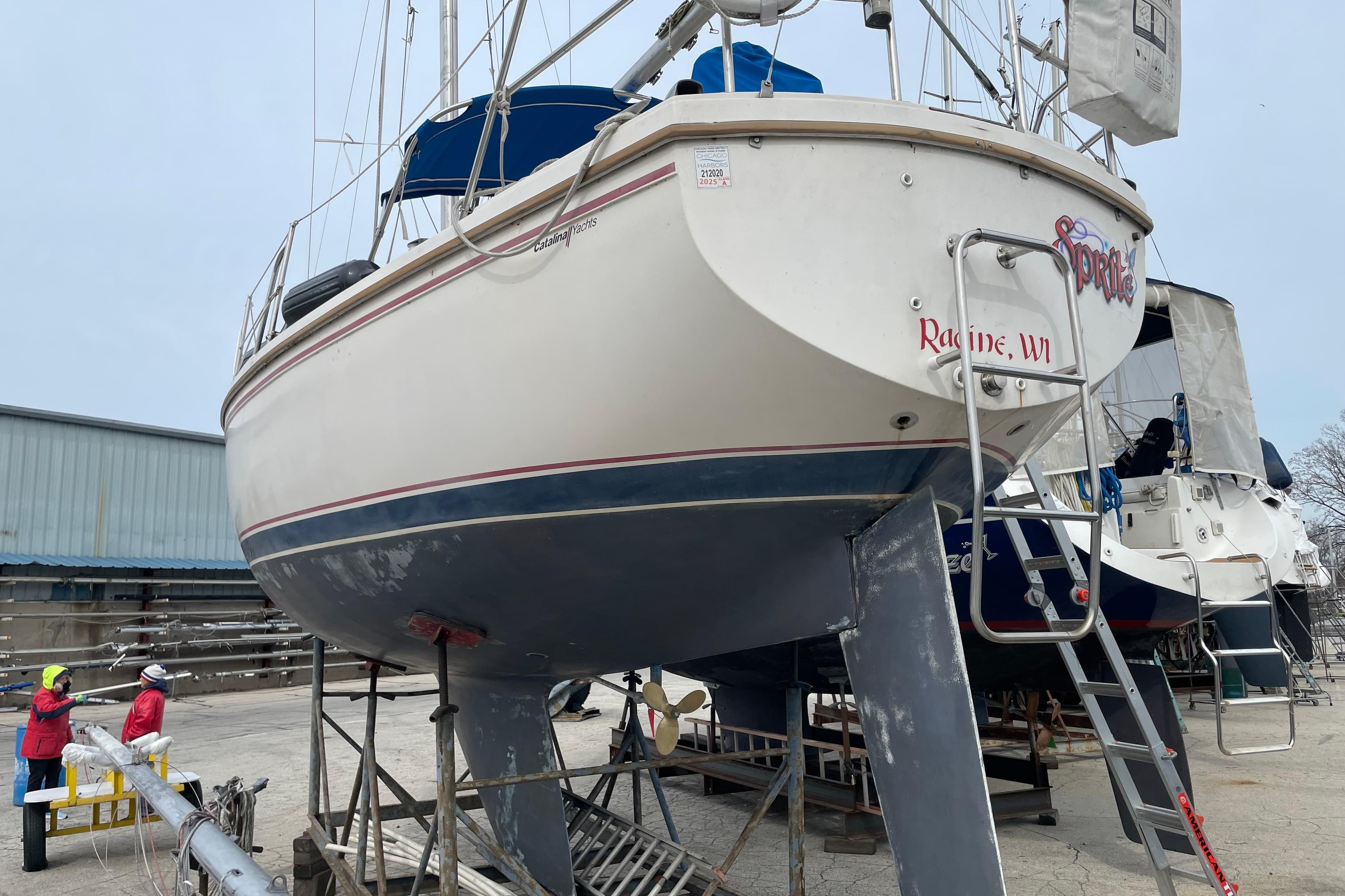 1989 Catalina 30 sailboat on dry dock in Racine, WI, with maintenance crew nearby.