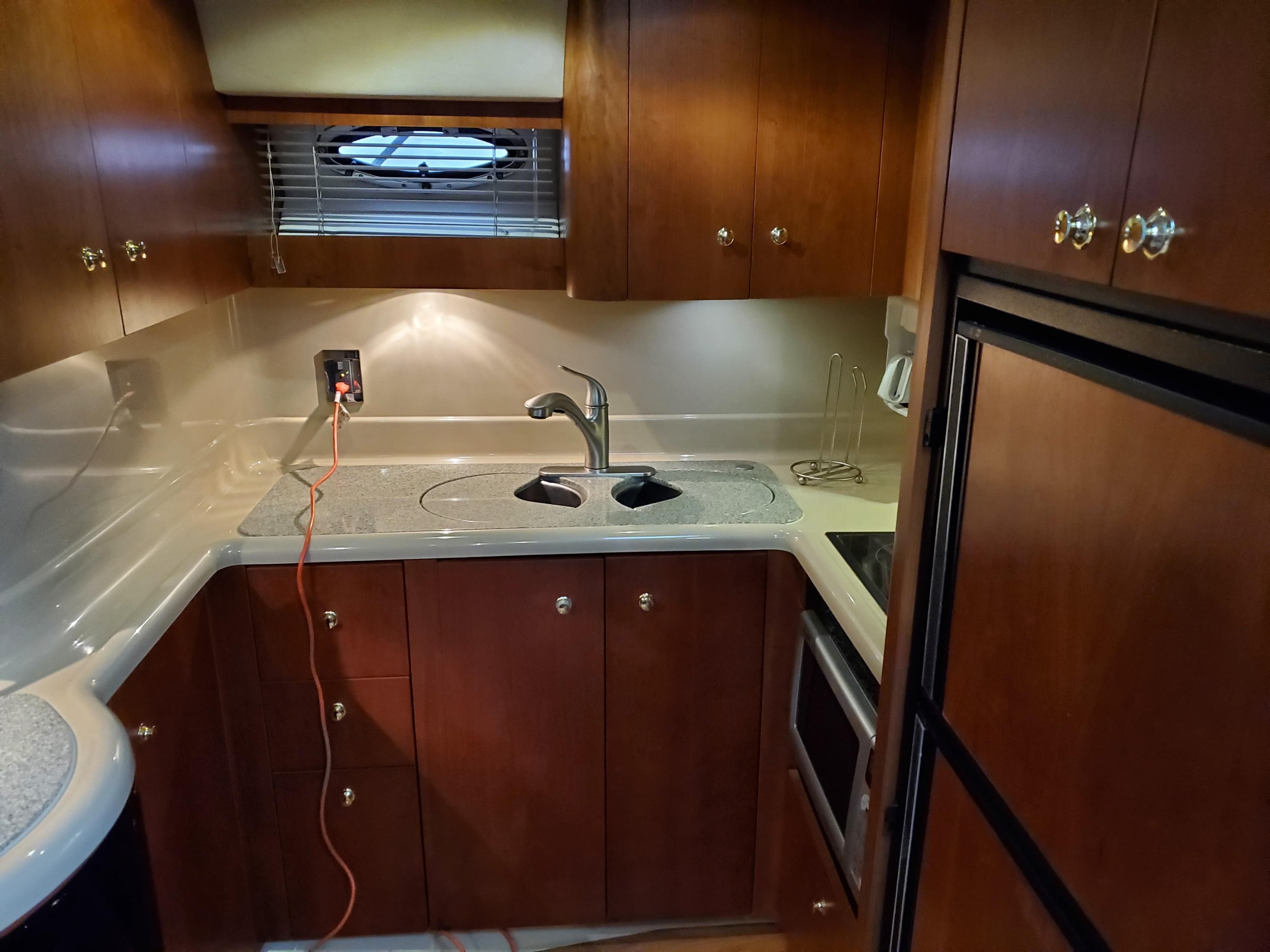 2002 Cruisers Yachts 4270 Express kitchen with wooden cabinets and modern appliances.
