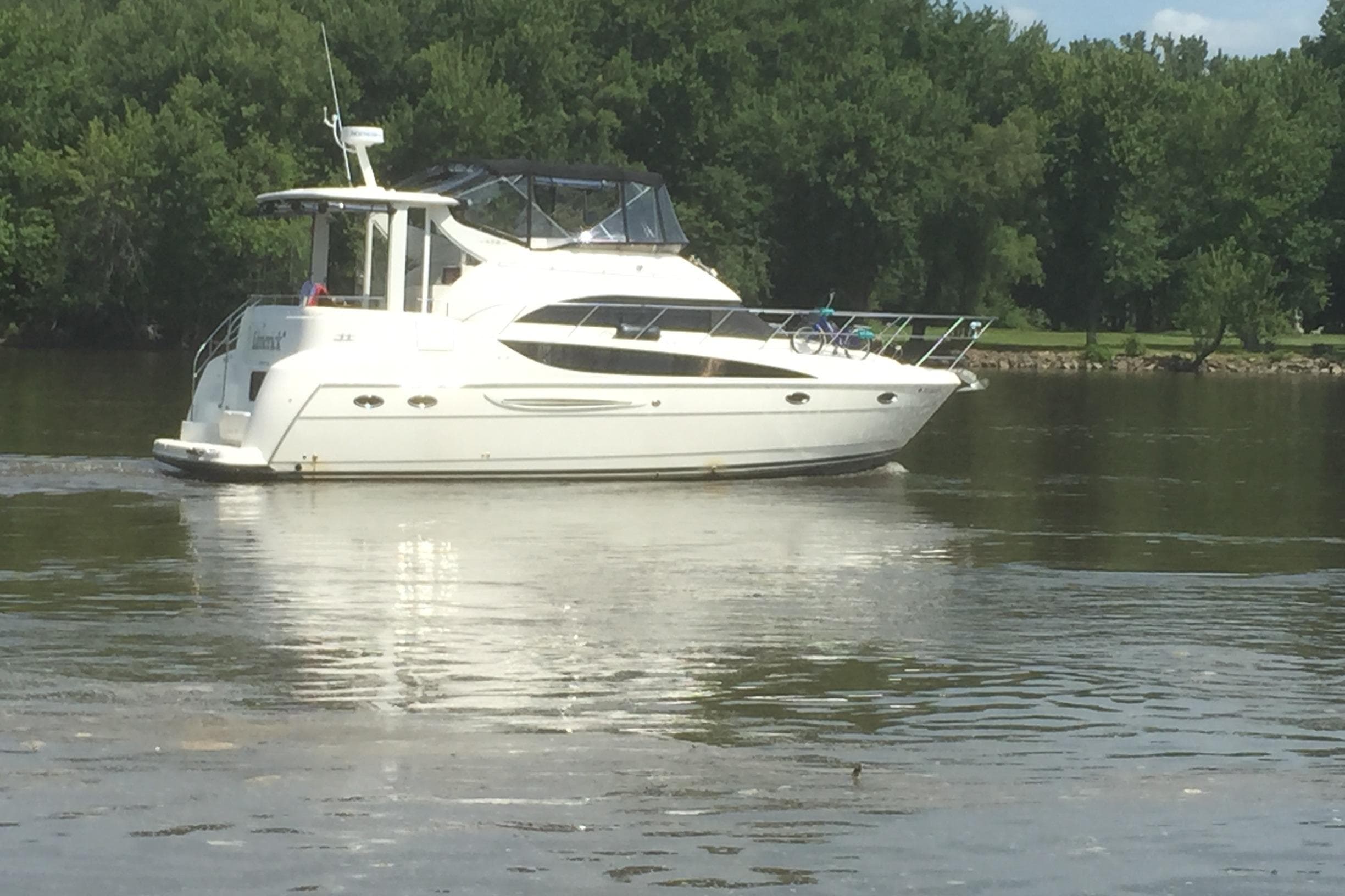 2006 Meridian 408 Motoryacht cruising on a calm river with lush green trees.