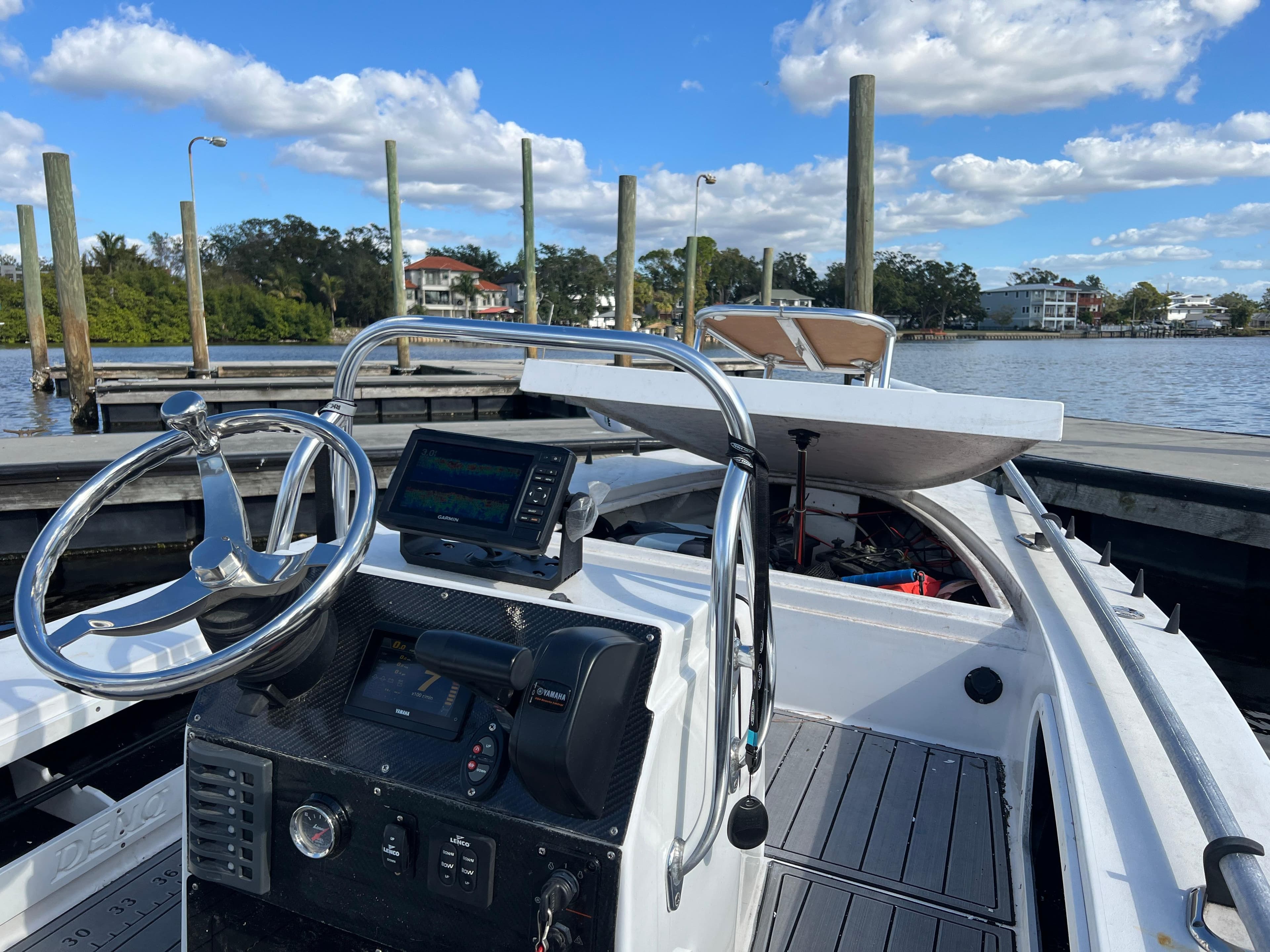 2024 Deno 17 Flats boat at dock, featuring steering wheel and navigation system.