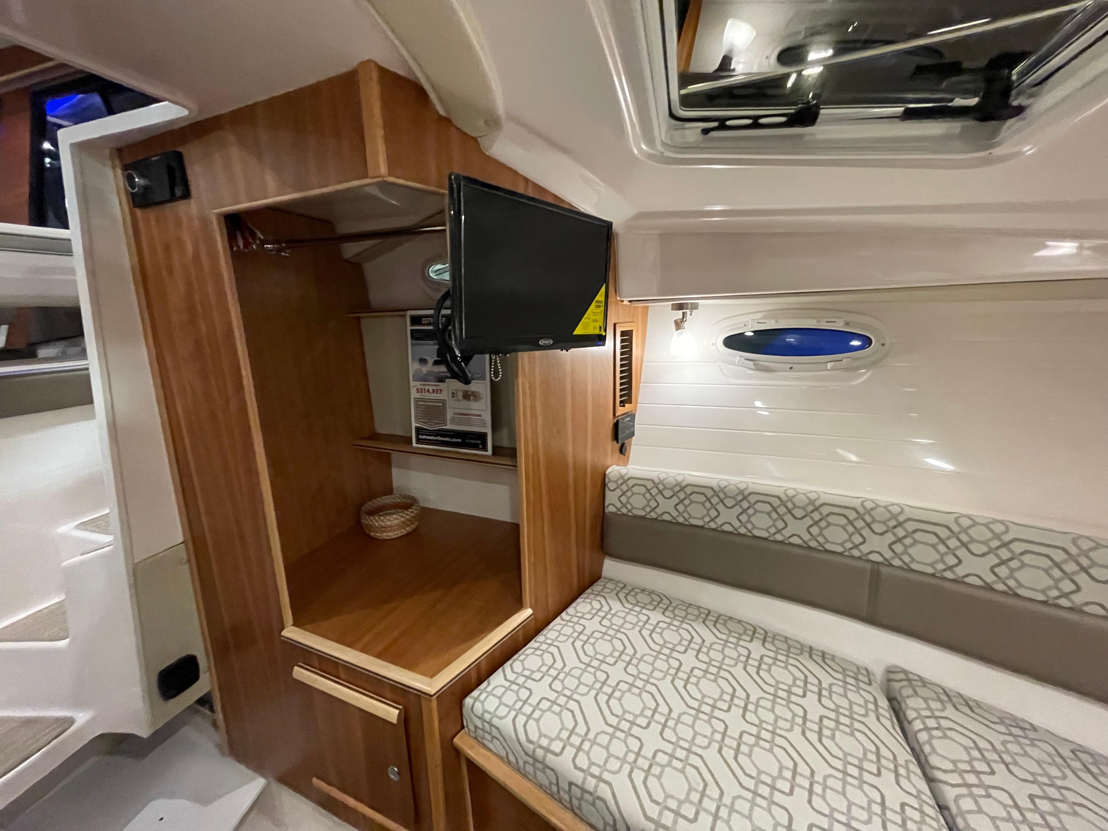 2026 Cutwater C-288 Coupe interior with wood cabinetry, TV, and patterned seating.