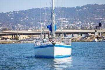 1989 Wauquiez Centurion 47 sailboat on calm water with cityscape background.