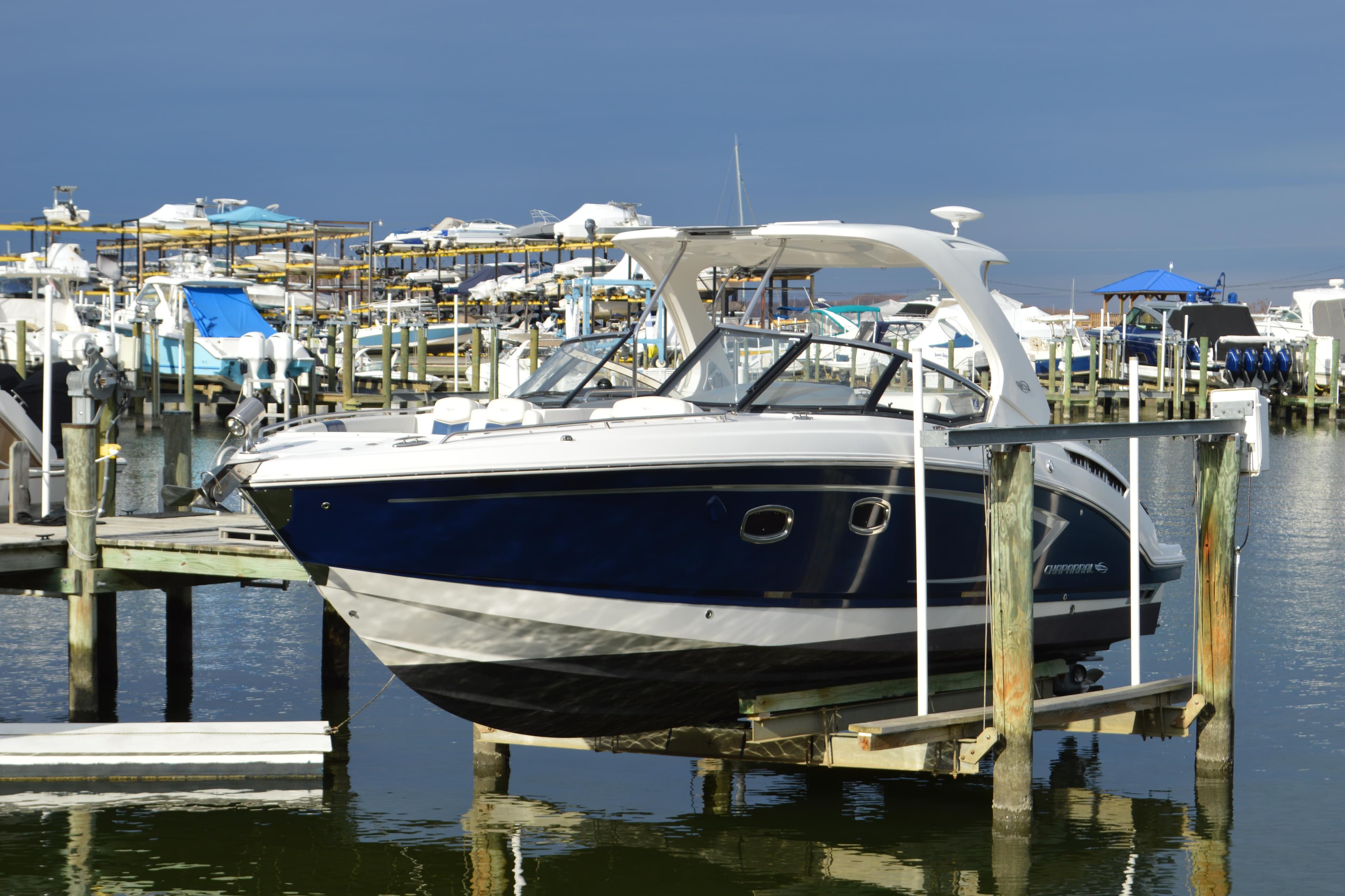 2013 Chaparral 327 SSX boat docked at a marina, surrounded by other vessels.