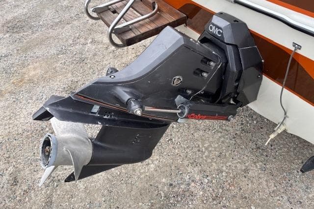 1986 Galaxie Bowrider boat with OMC outboard motor on gravel surface.