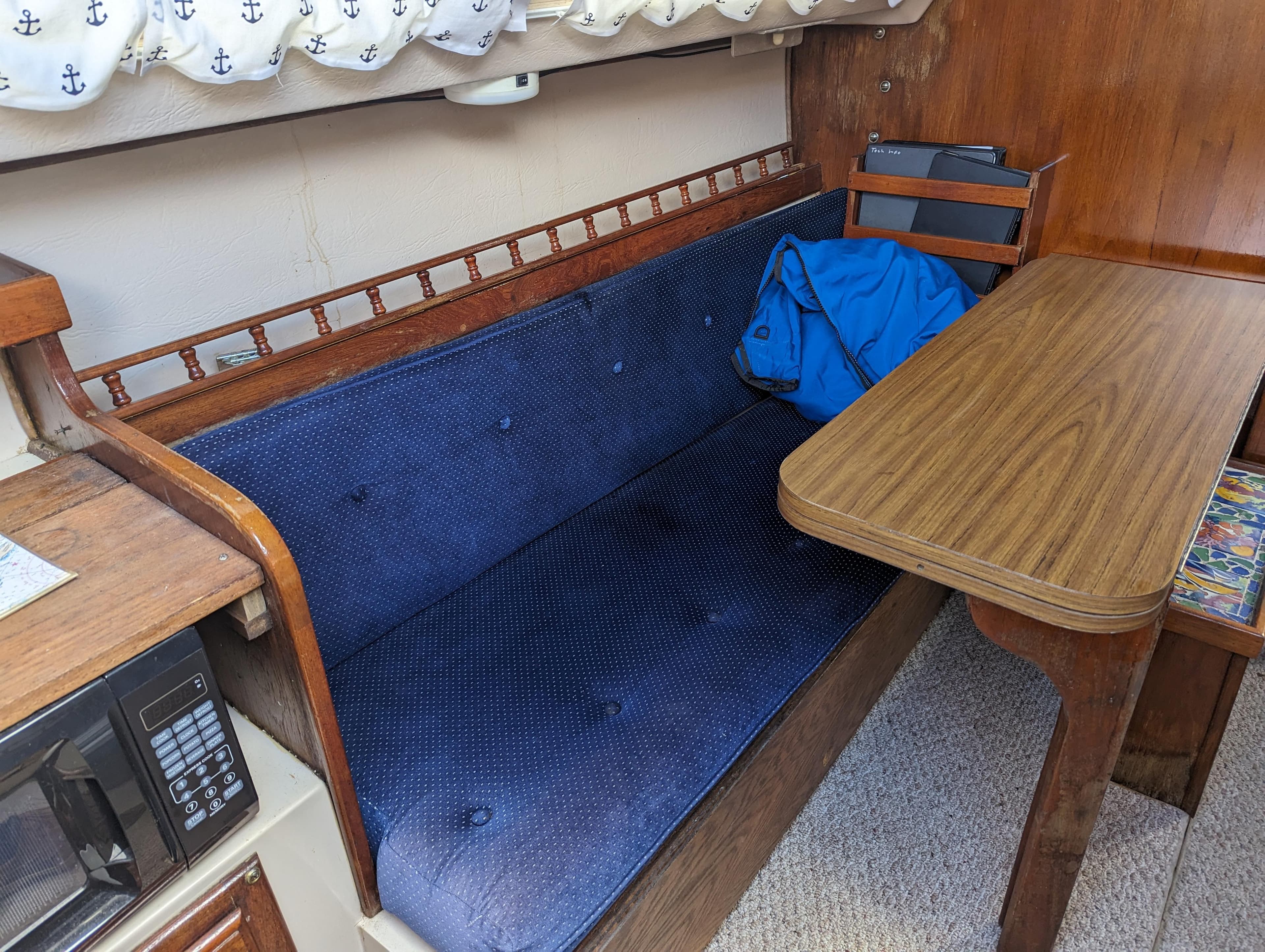 Interior of a 1987 Catalina 25 sailboat with blue cushioned seating and wooden table.
