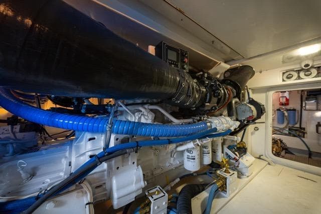 Engine room of a 1997 Garlington Convertible boat, showcasing complex machinery and blue hoses.