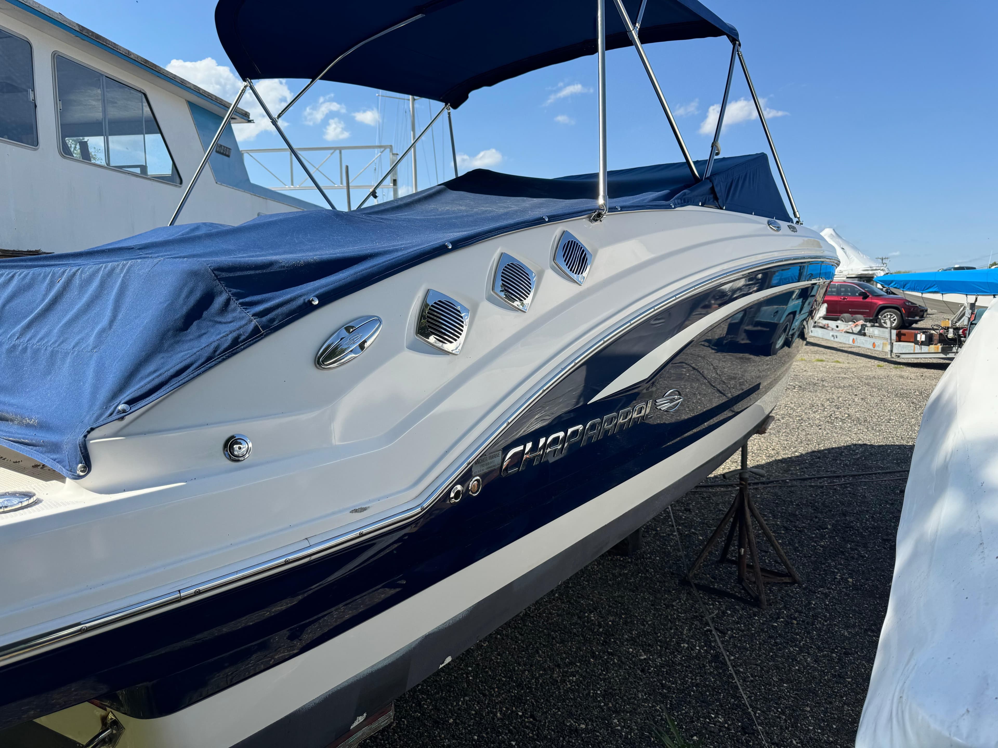 2014 Chaparral 246 SSi boat with blue cover and canopy, docked outdoors.