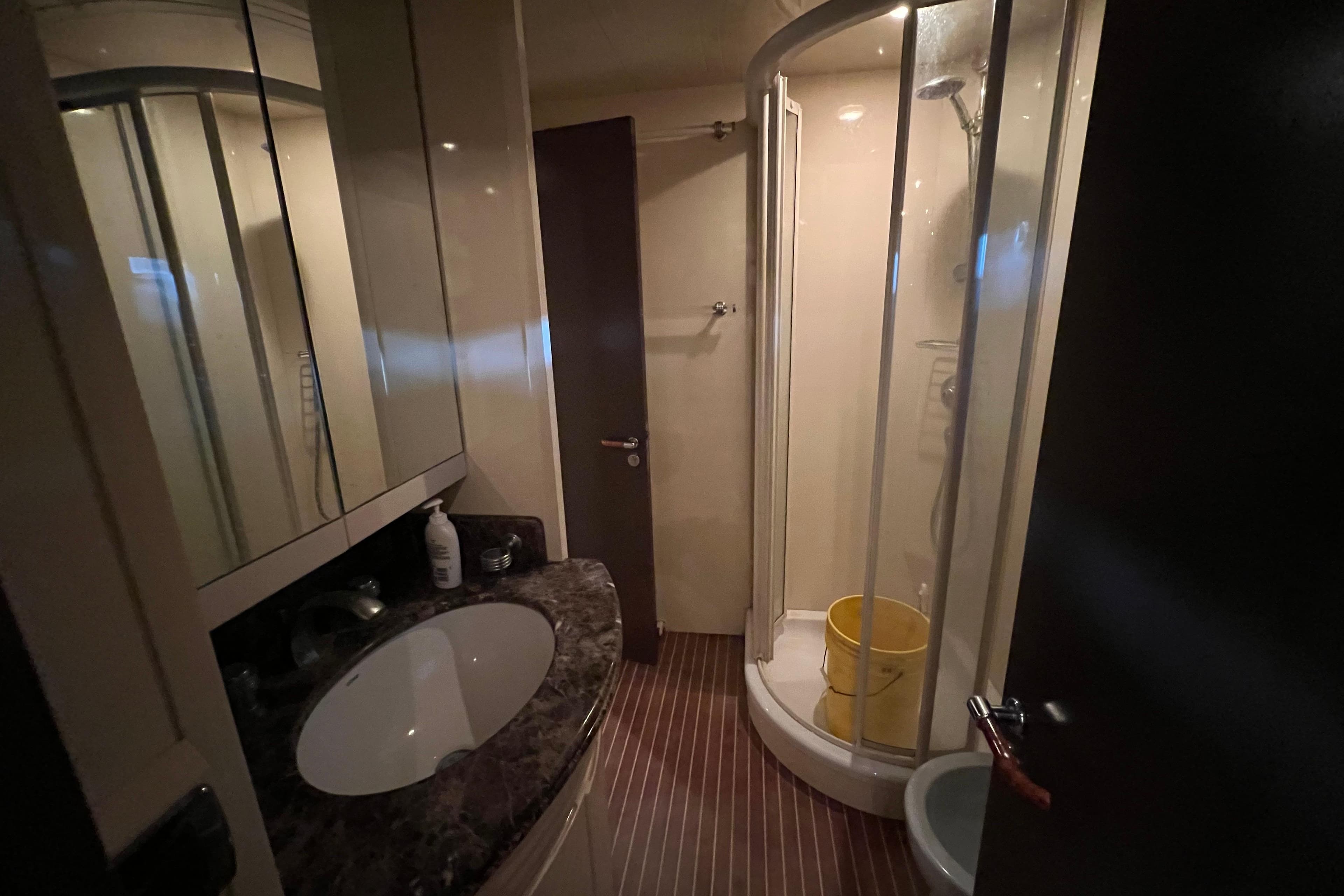 Compact bathroom in 2001 Falcon 106 yacht with shower and marble countertop.