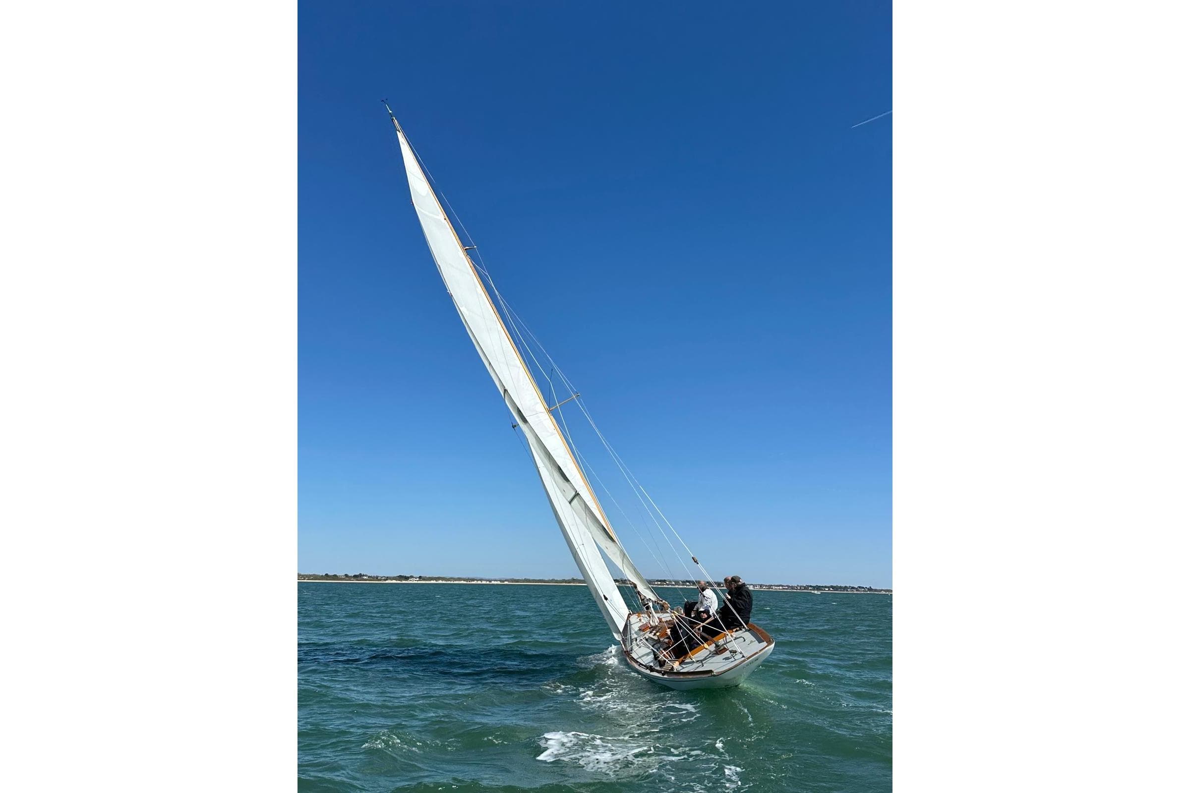 Classic 1924 West Solent One Design "ARROW" sailing on open water under clear blue sky.