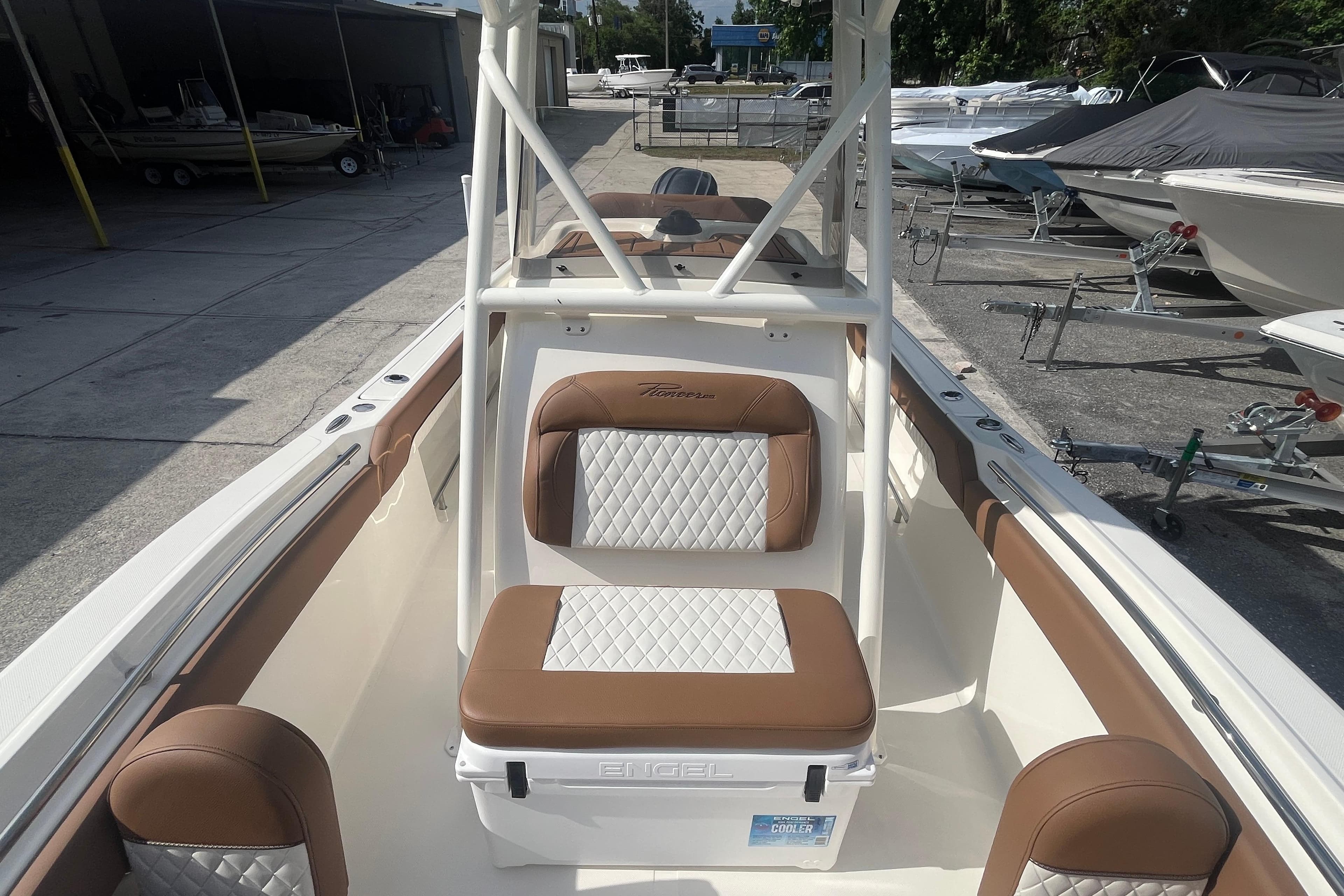 2026 Pioneer 222 Islander boat interior with brown and white seating, docked at a marina.