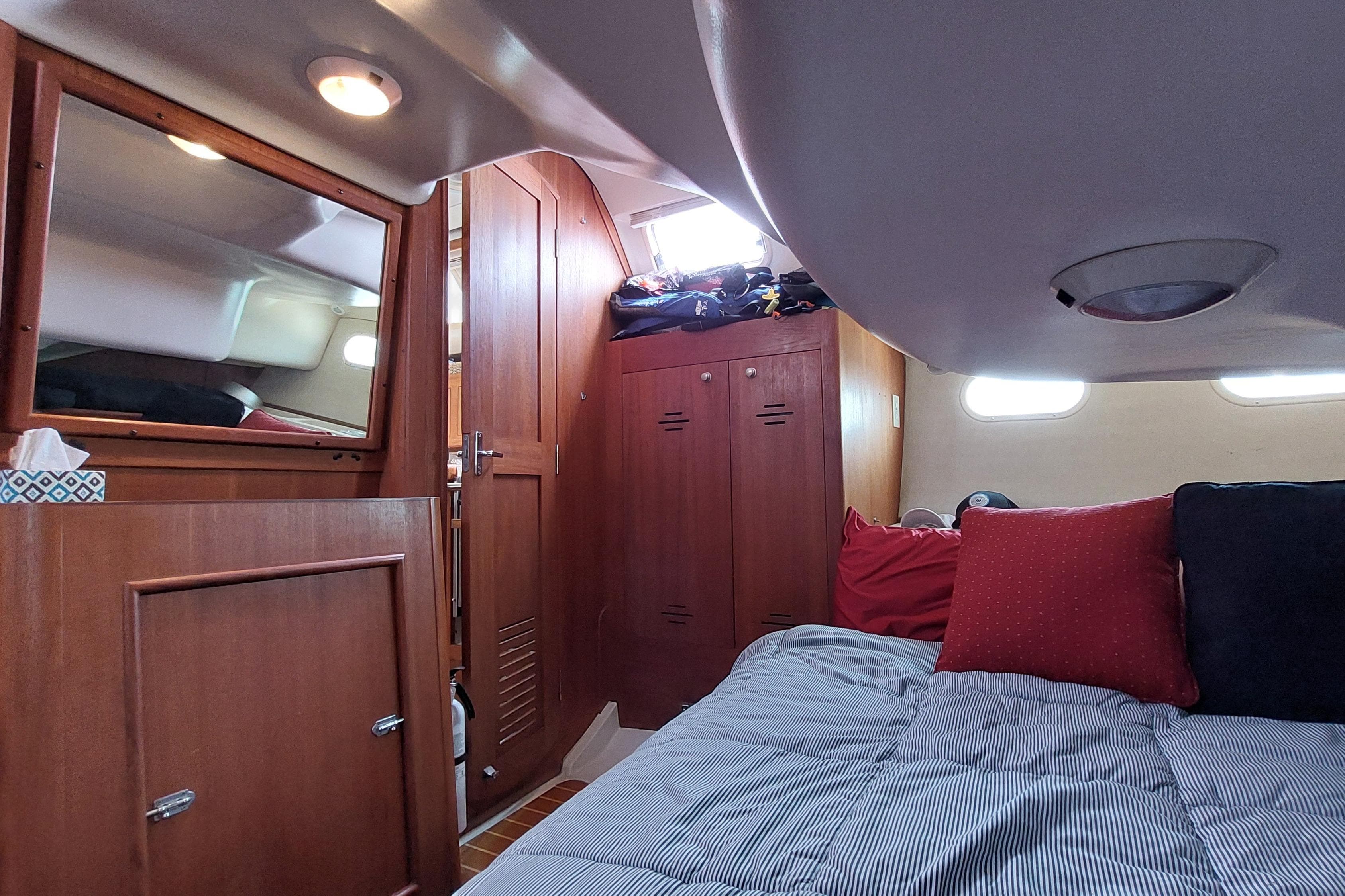 Cozy cabin interior of a 2002 Hunter 380 sailboat with wooden furnishings and bedding.