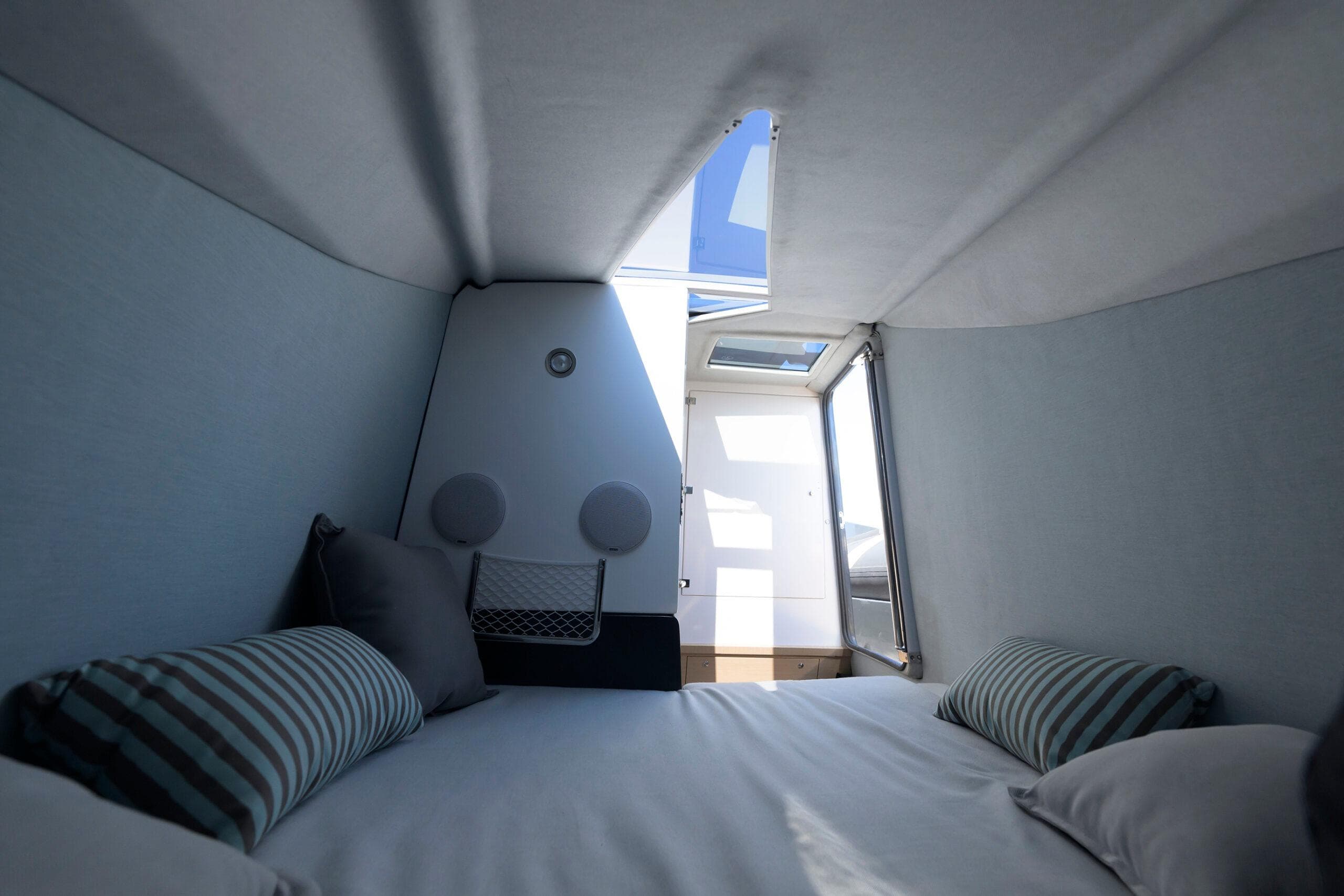 2024 Tropida Cosmic 39 cabin interior with skylight, cozy bedding, and striped pillows.