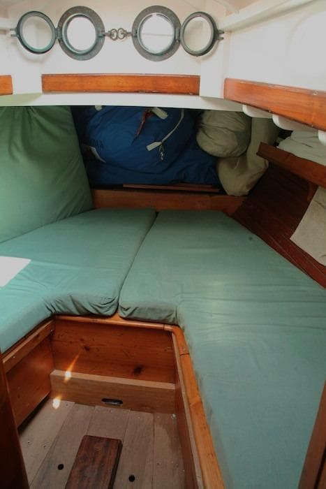 1958 Concordia Yawl cabin interior with green cushions and wooden trim.