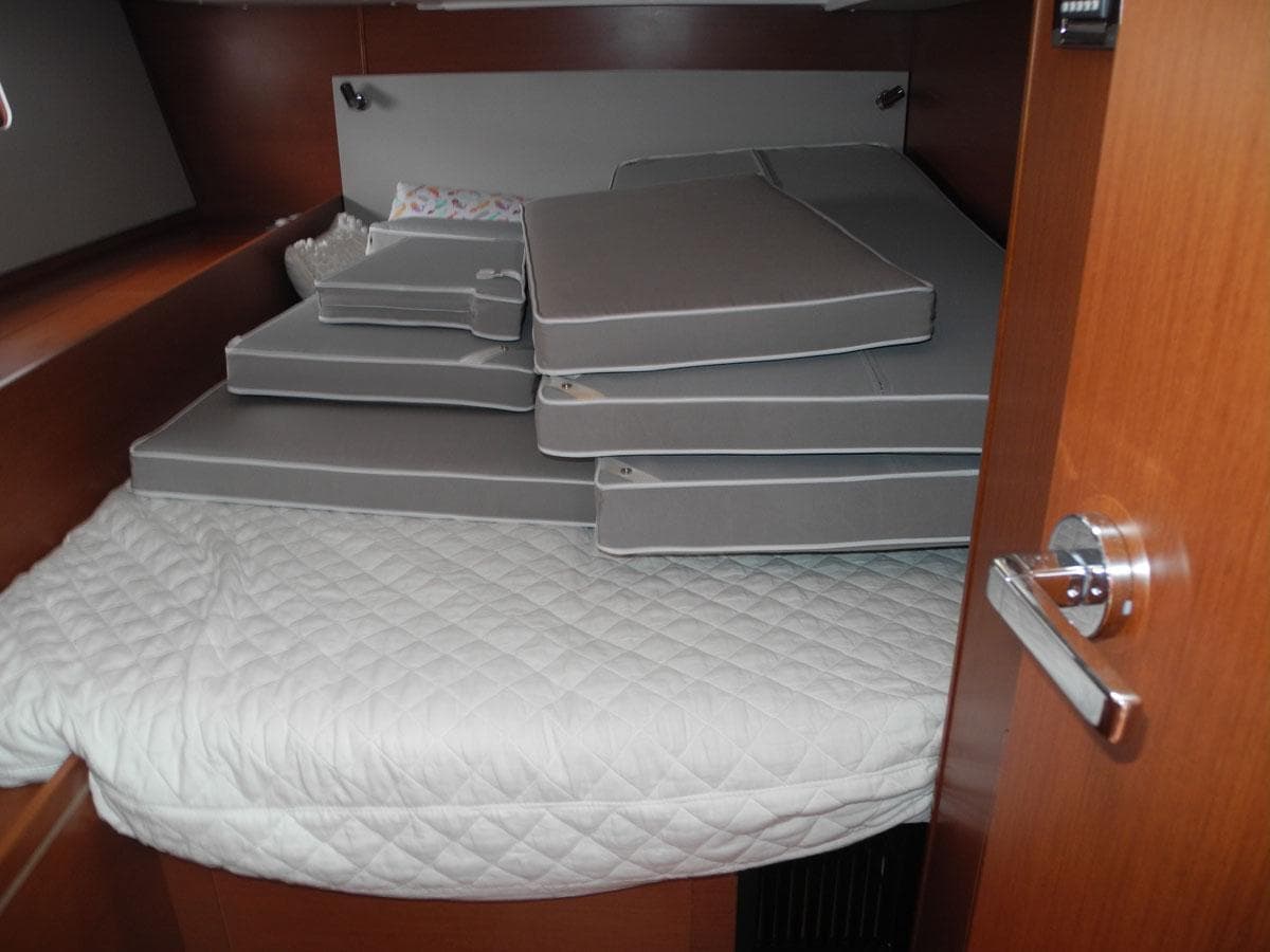 Cabin interior of 2020 Beneteau Oceanis 51.1 with stacked cushions on bed.