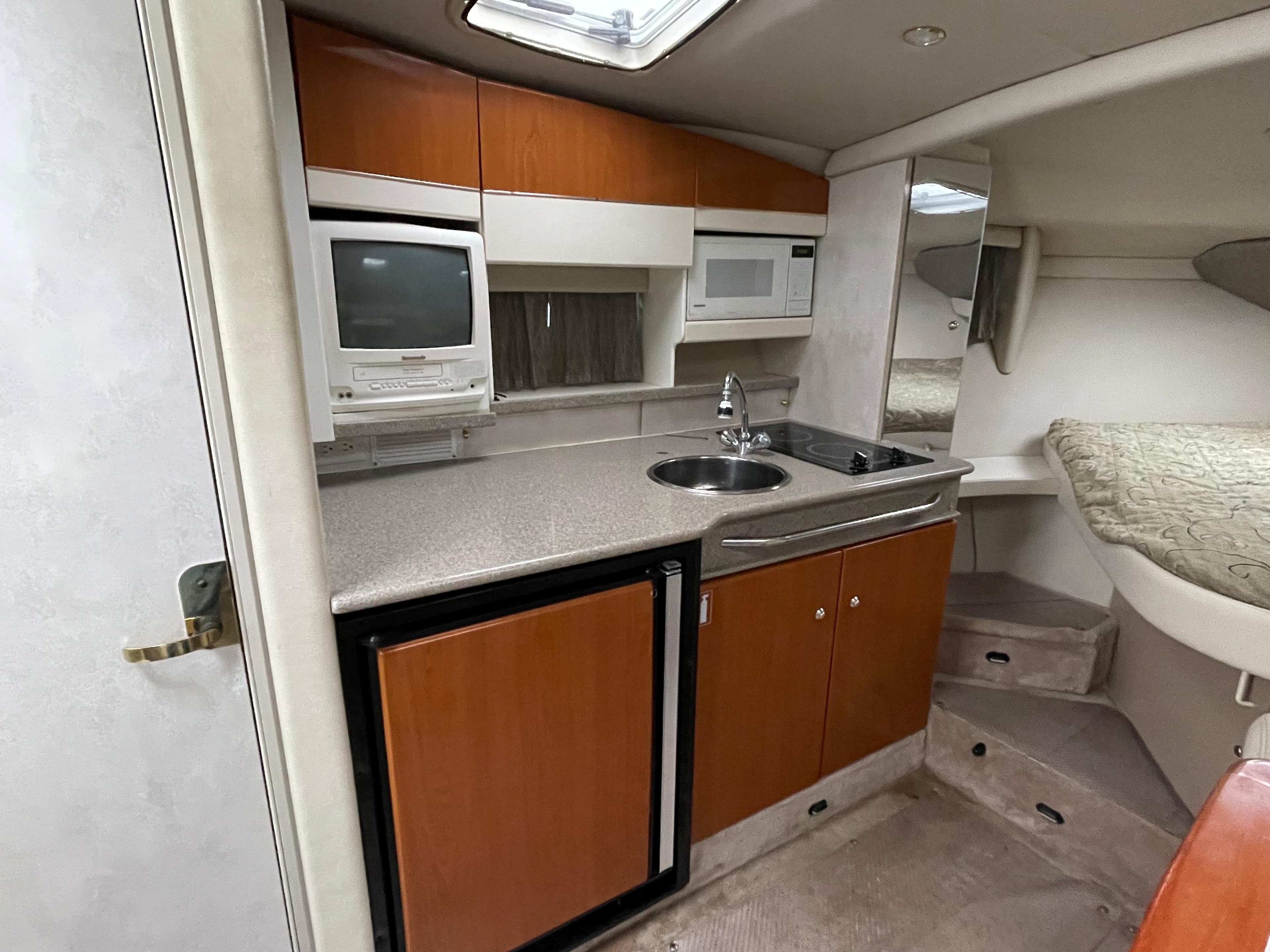 2002 Formula 31 PC boat interior kitchen with sink, microwave, and fridge.