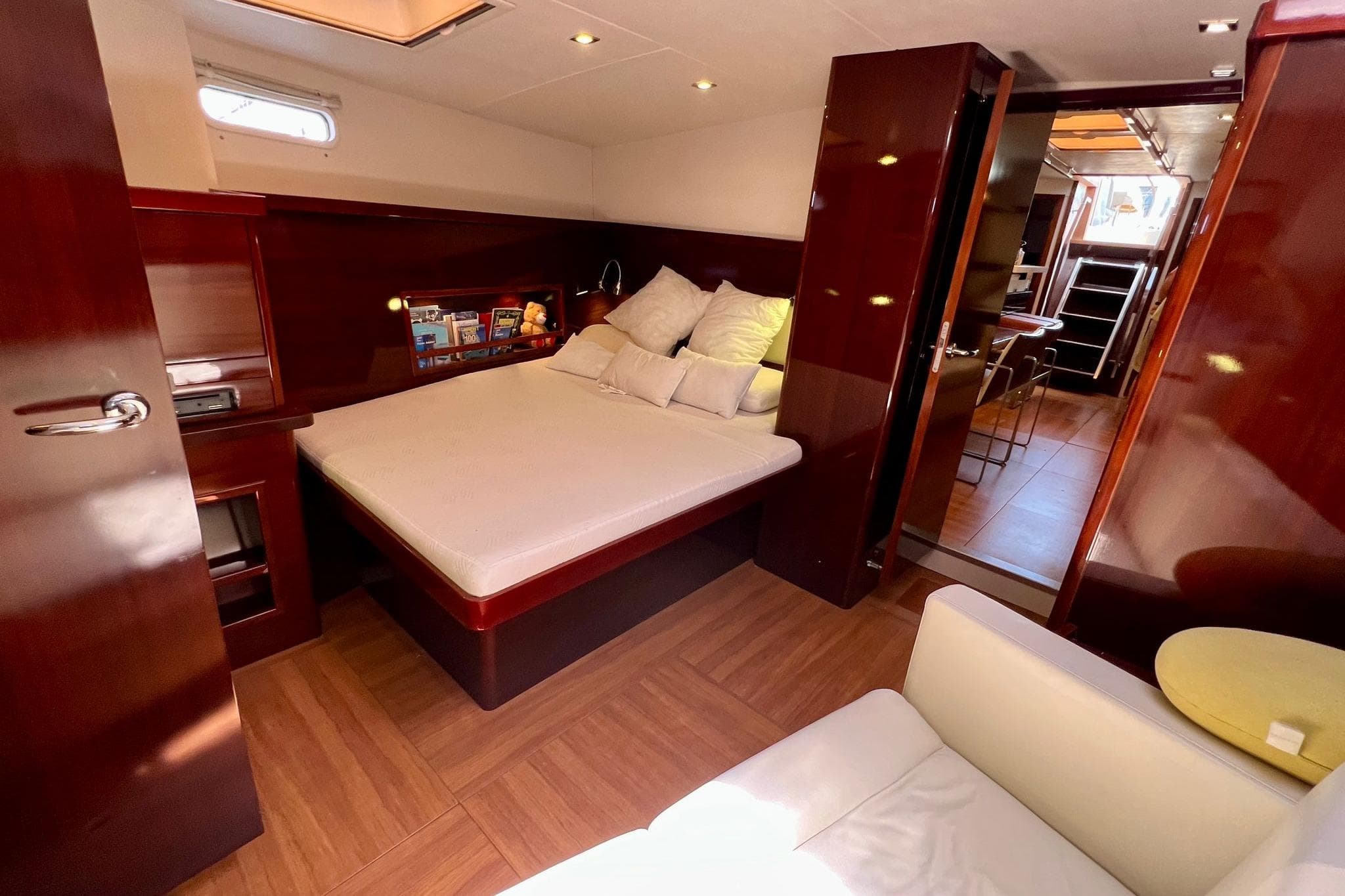 Luxurious cabin interior of 2010 Hanse 630 e yacht with cozy bed and elegant wood finish.