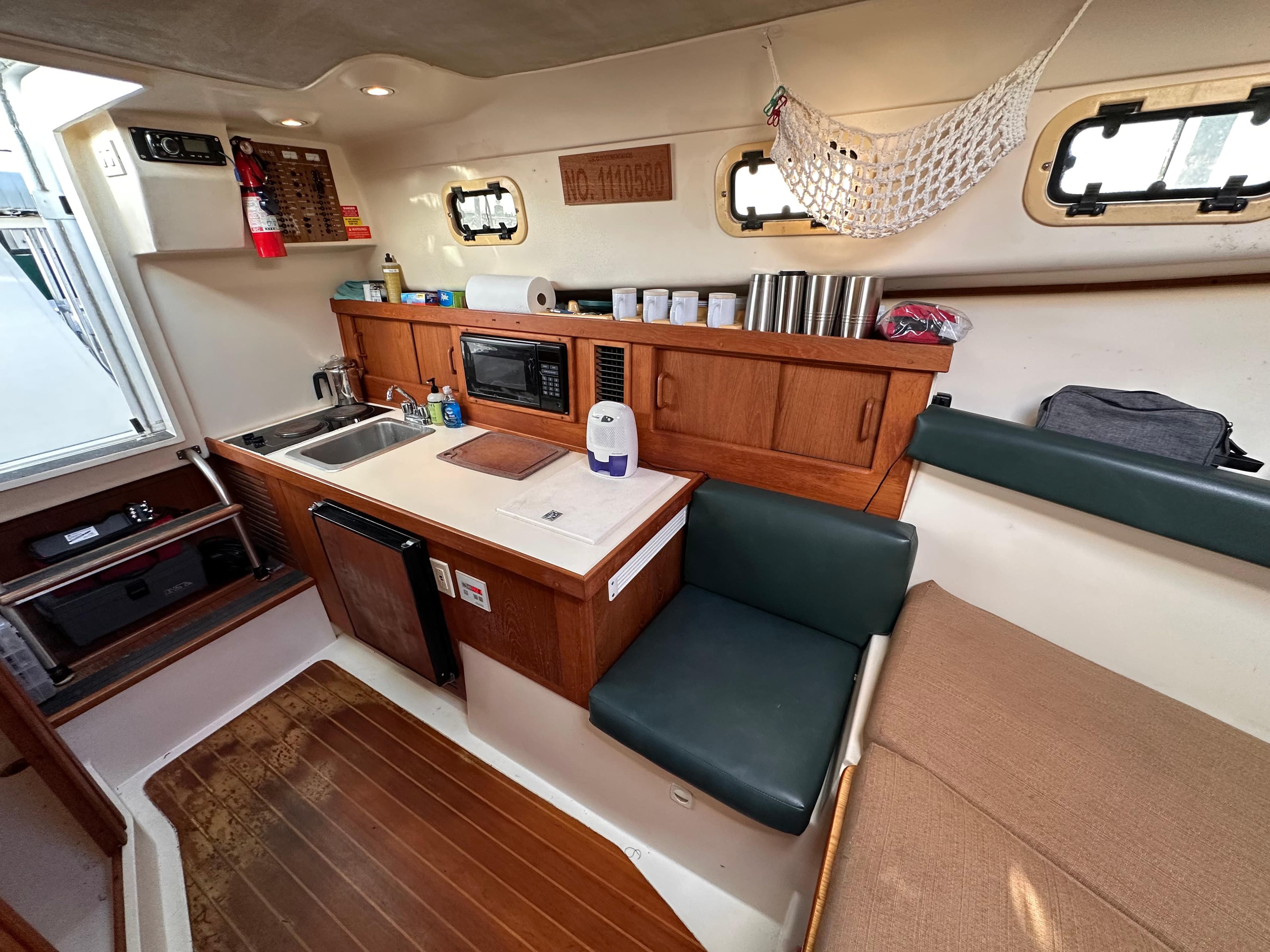 2001 Mainship Pilot 30 interior with kitchenette, seating, and storage. Cozy and functional boat cabin.
