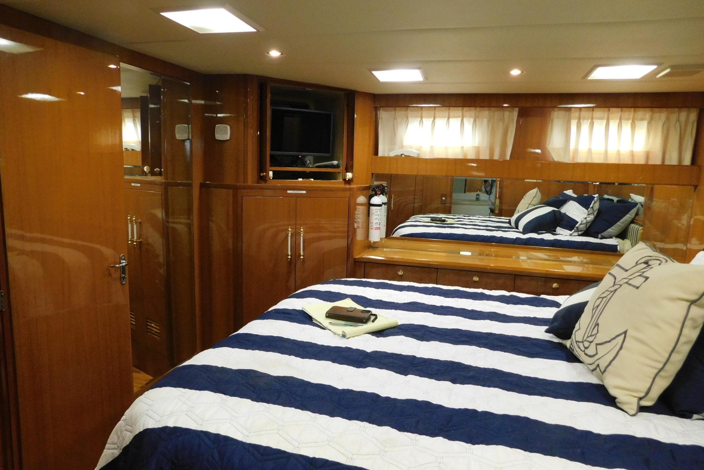 Luxurious bedroom interior of 2001 Jefferson Pilothouse 57 yacht with striped bedding and wood finishes.