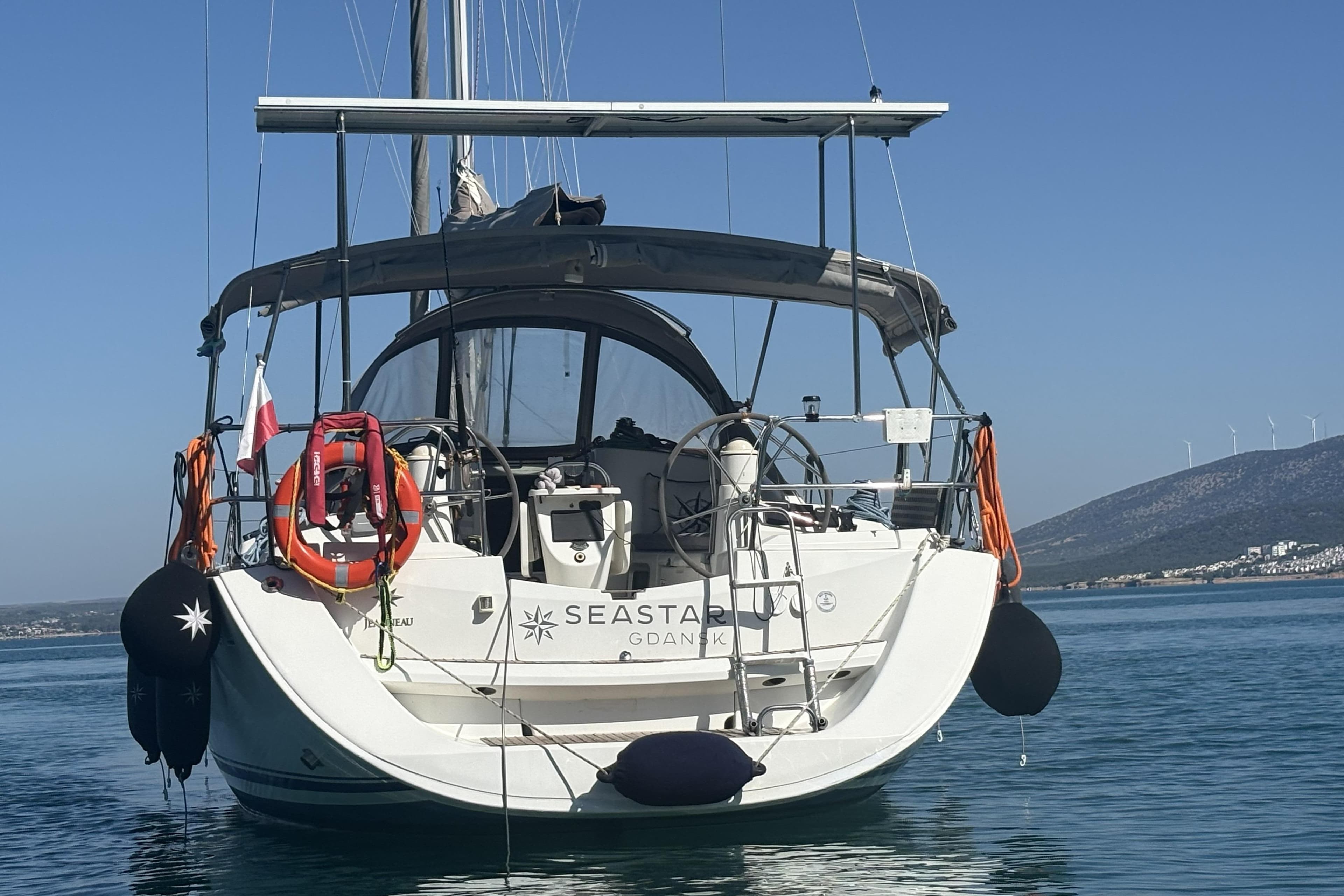 2008 Jeanneau Sun Odyssey 39i sailboat on calm water, rear view with clear sky.