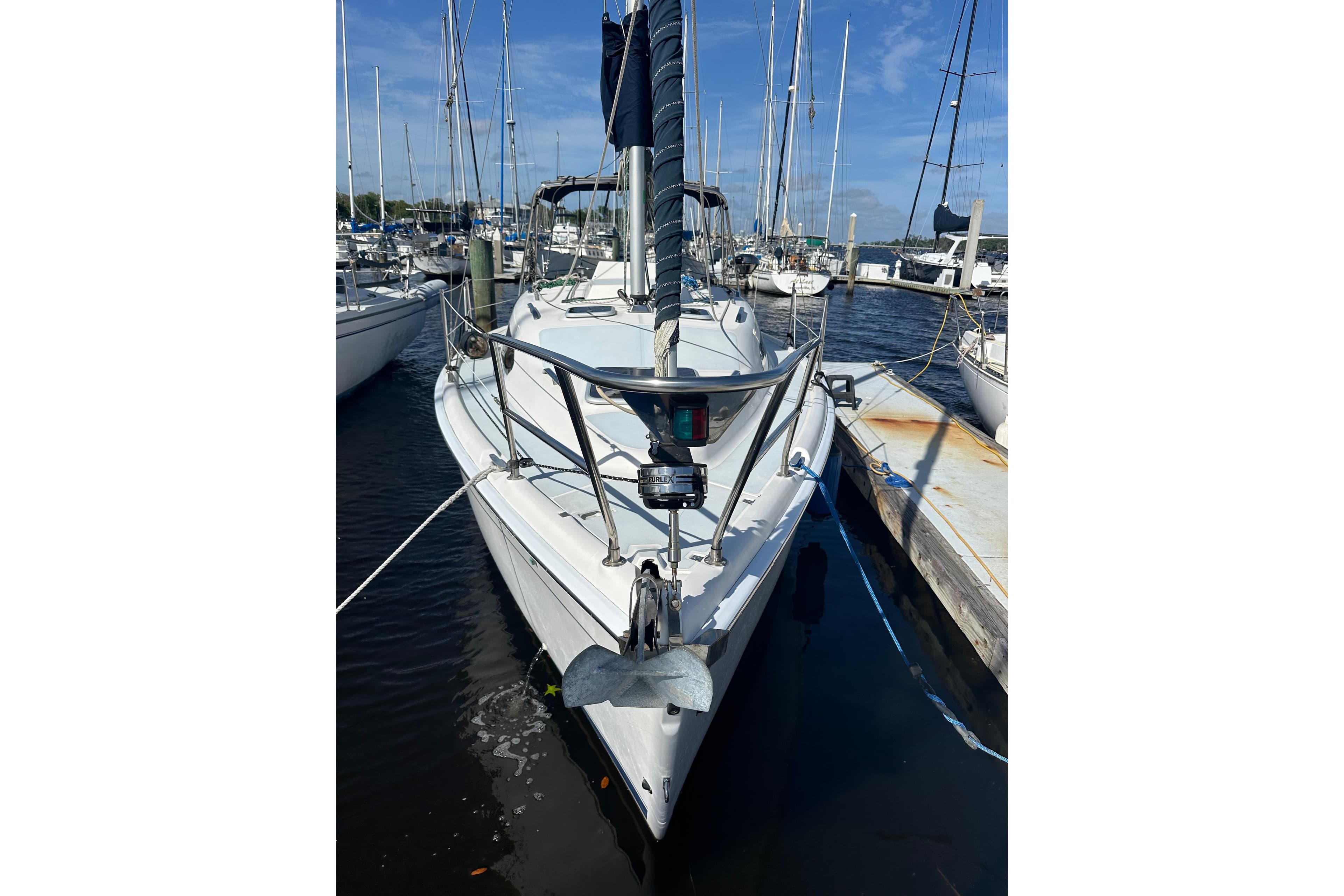 2002 Hunter 306 sailboat docked at marina under clear blue sky.