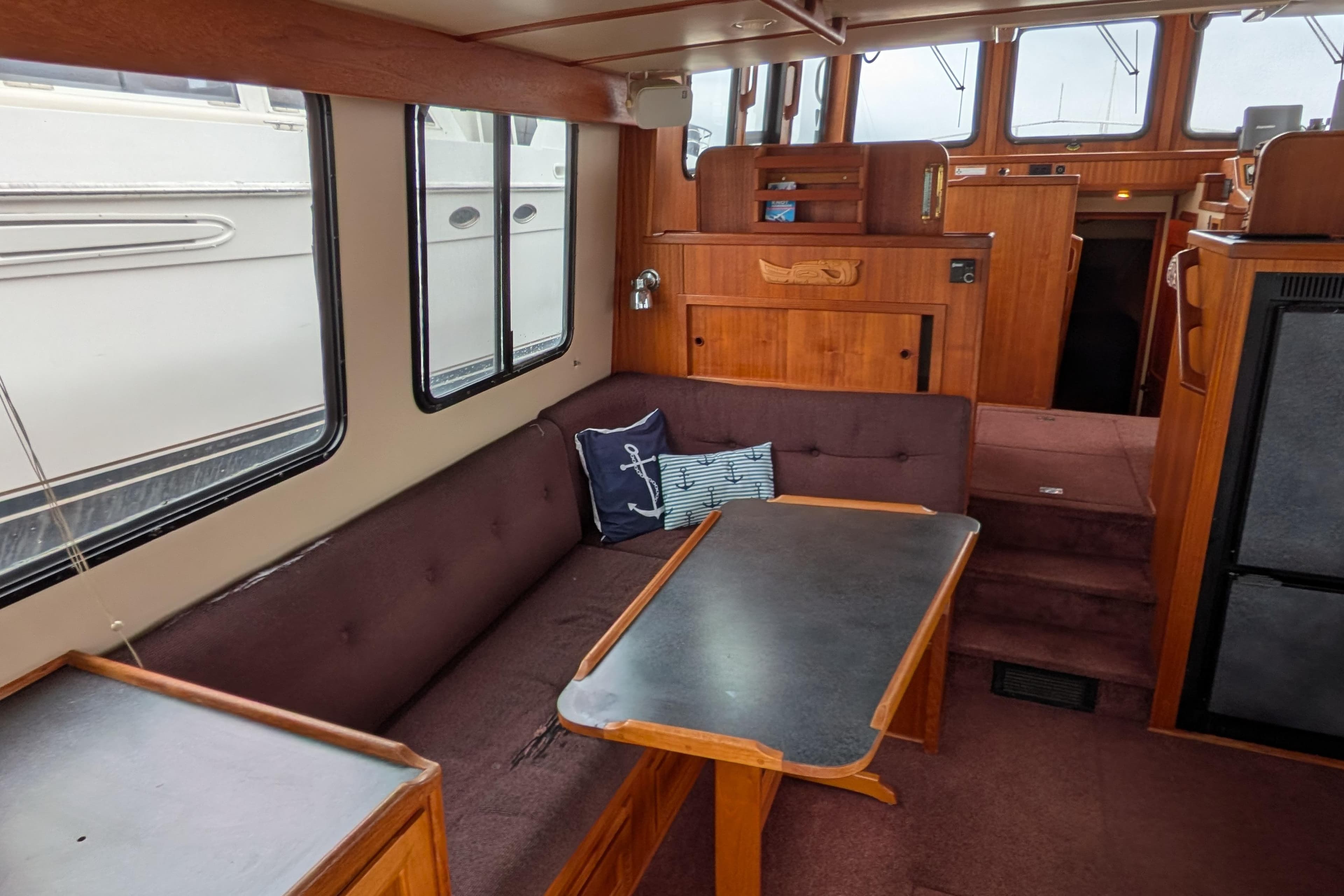Interior of a 2000 Nordic Tug 37, featuring a cozy seating area and wooden cabinetry.