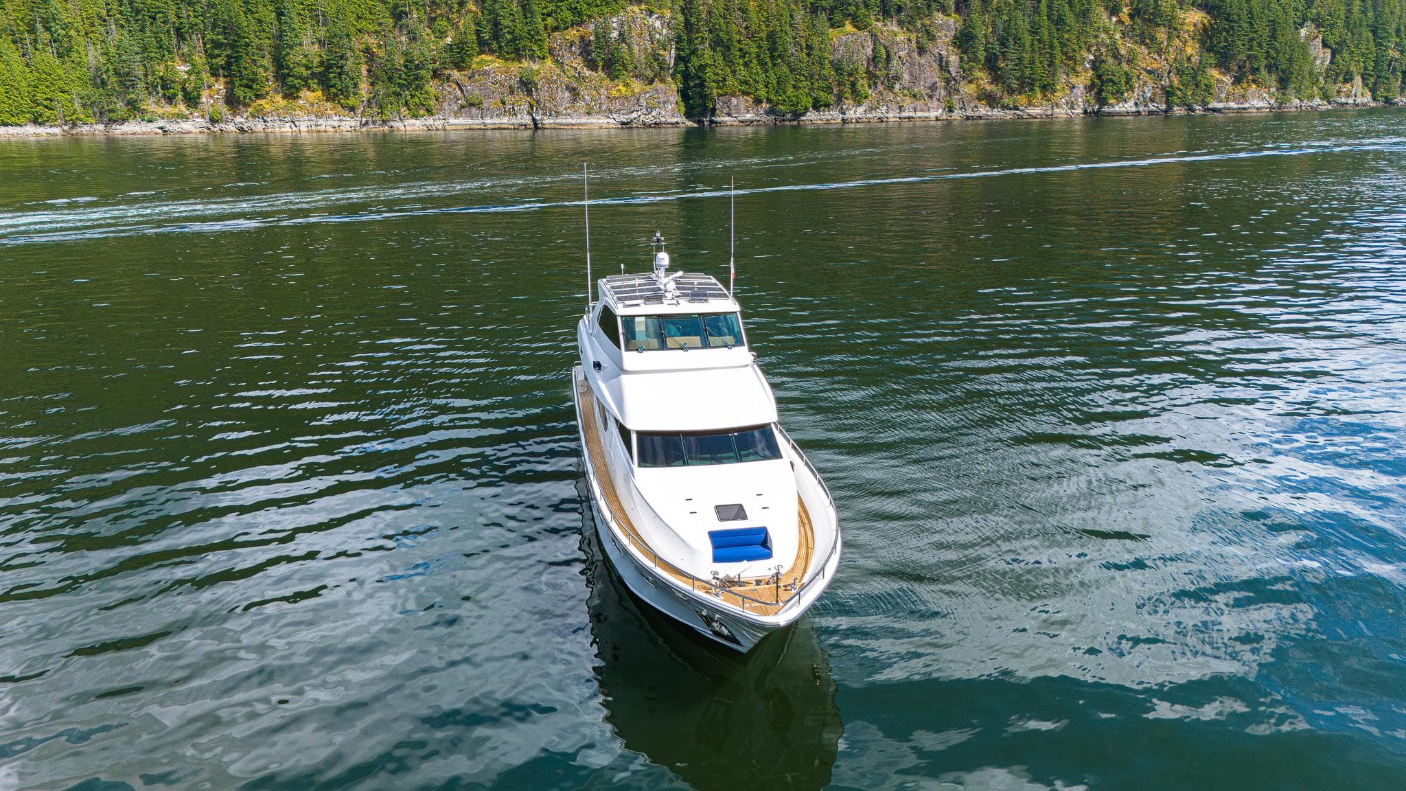 Luxurious 2007 Mystica Skylounge yacht cruising on a serene lake with forested shoreline.