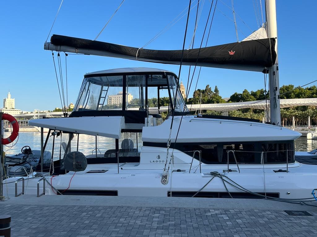 2023 Lagoon 51 catamaran docked at a marina under clear blue skies.
