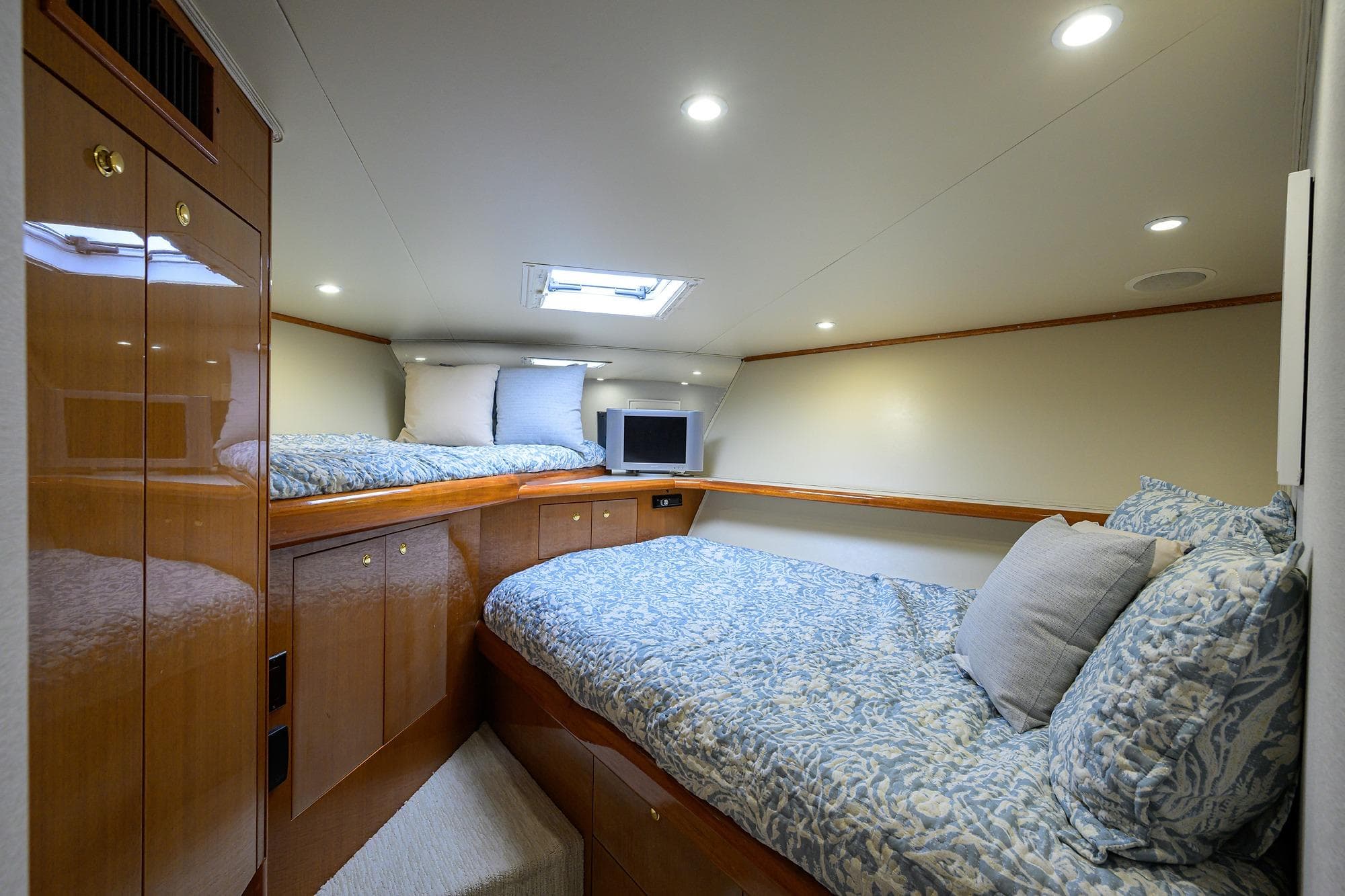 Luxurious cabin interior of 2004 Viking 56 Convertible yacht with cozy bedding and wood finishes.